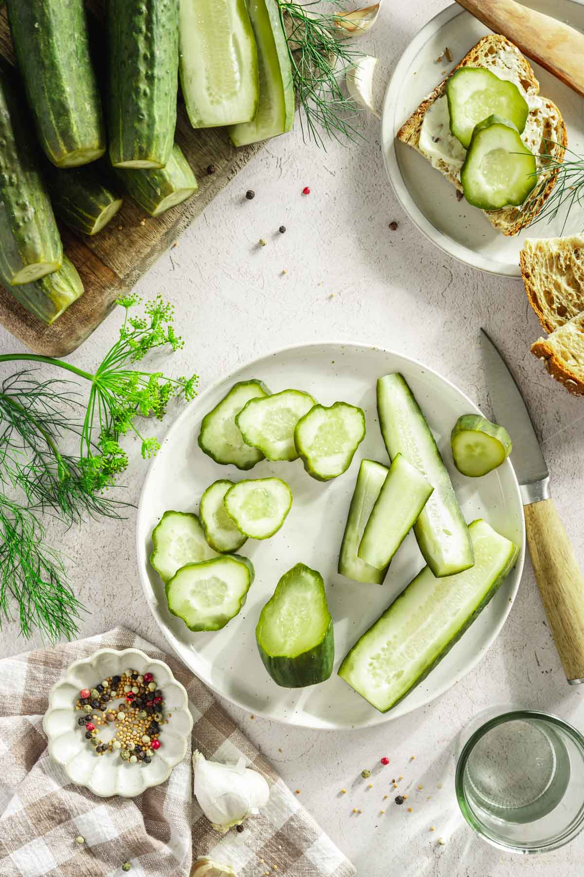 half sour pickles cut, sliced and arranged on a plate. Whole pickles on a cutting board,