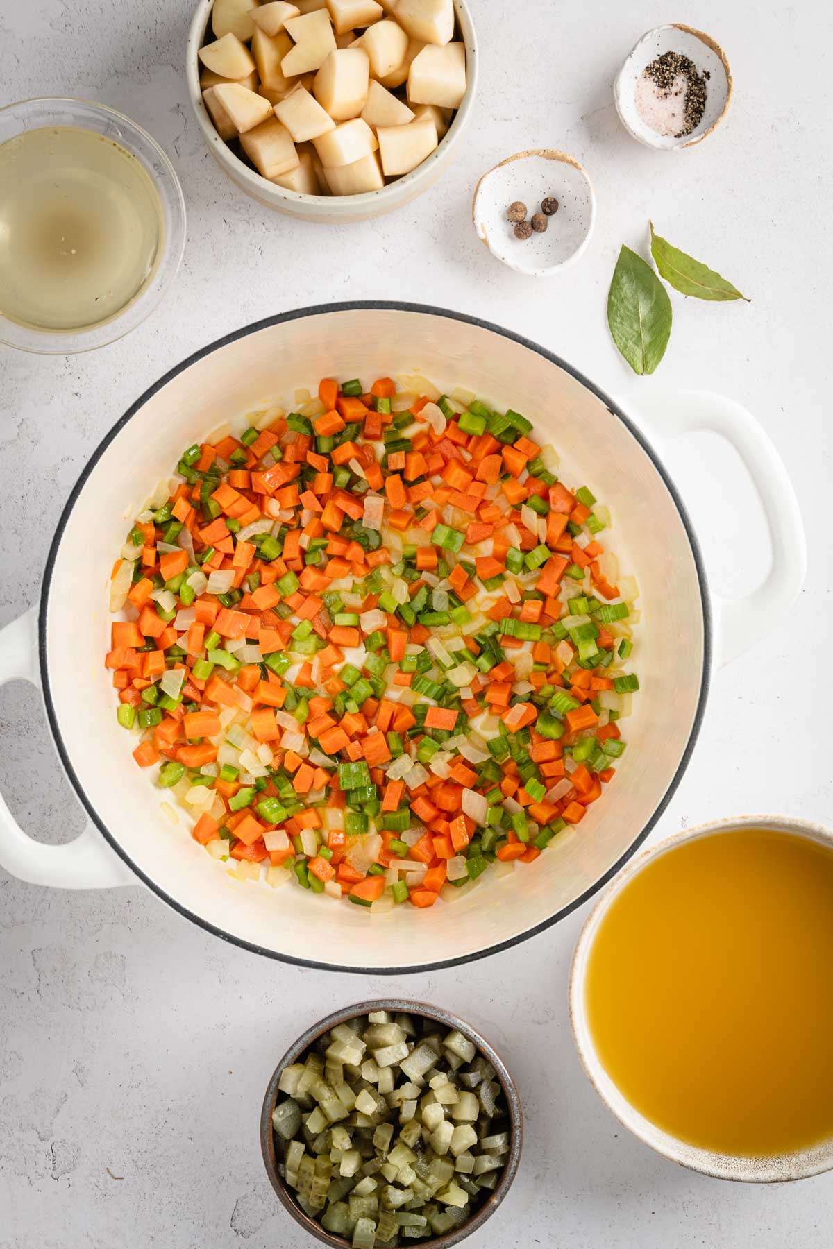 large stock pot with celery, onion and carrots cooked, other ingredients to make the soup are set arounf