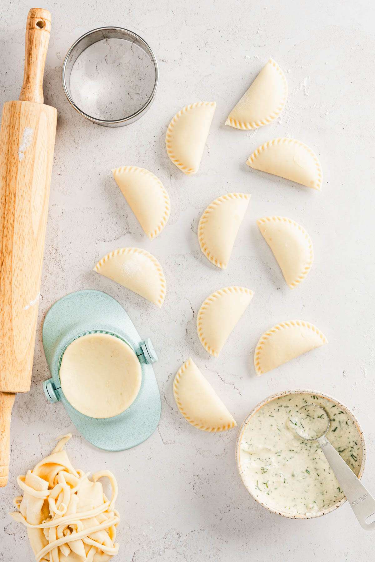 made raw pierogis, rolling pin, pierogi form, dish with the filling