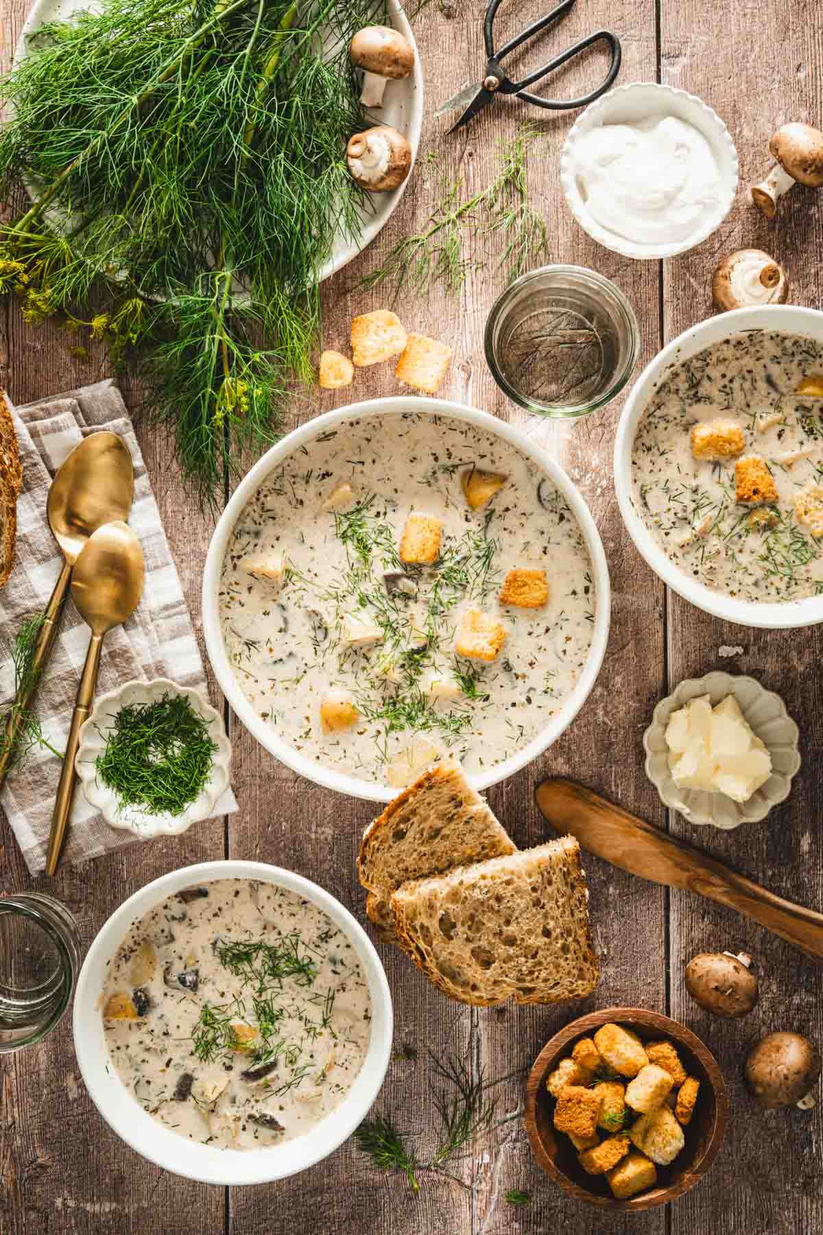 zupa koperkowa in a serving bowl, napkin, utensils, plate with butter, rustic bread, big bunch of dill, 