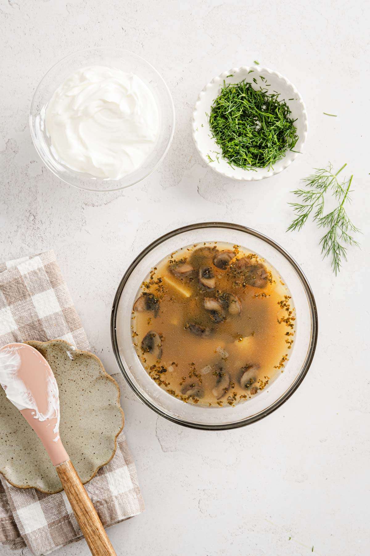 glass bowl with zupa koperkowa, dish with sour cream and fresh dill, spatula