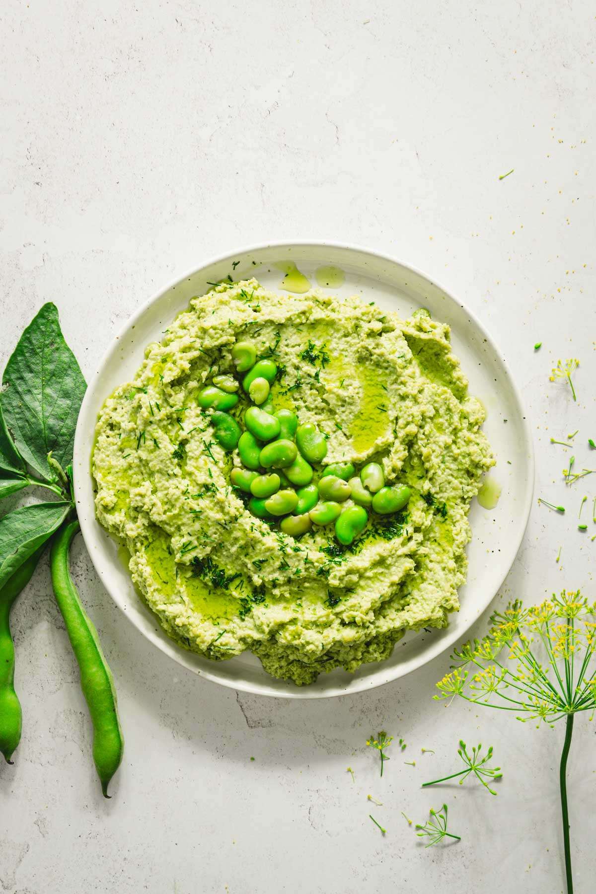 plate with fava bean hummus, fresh dill, bean pods