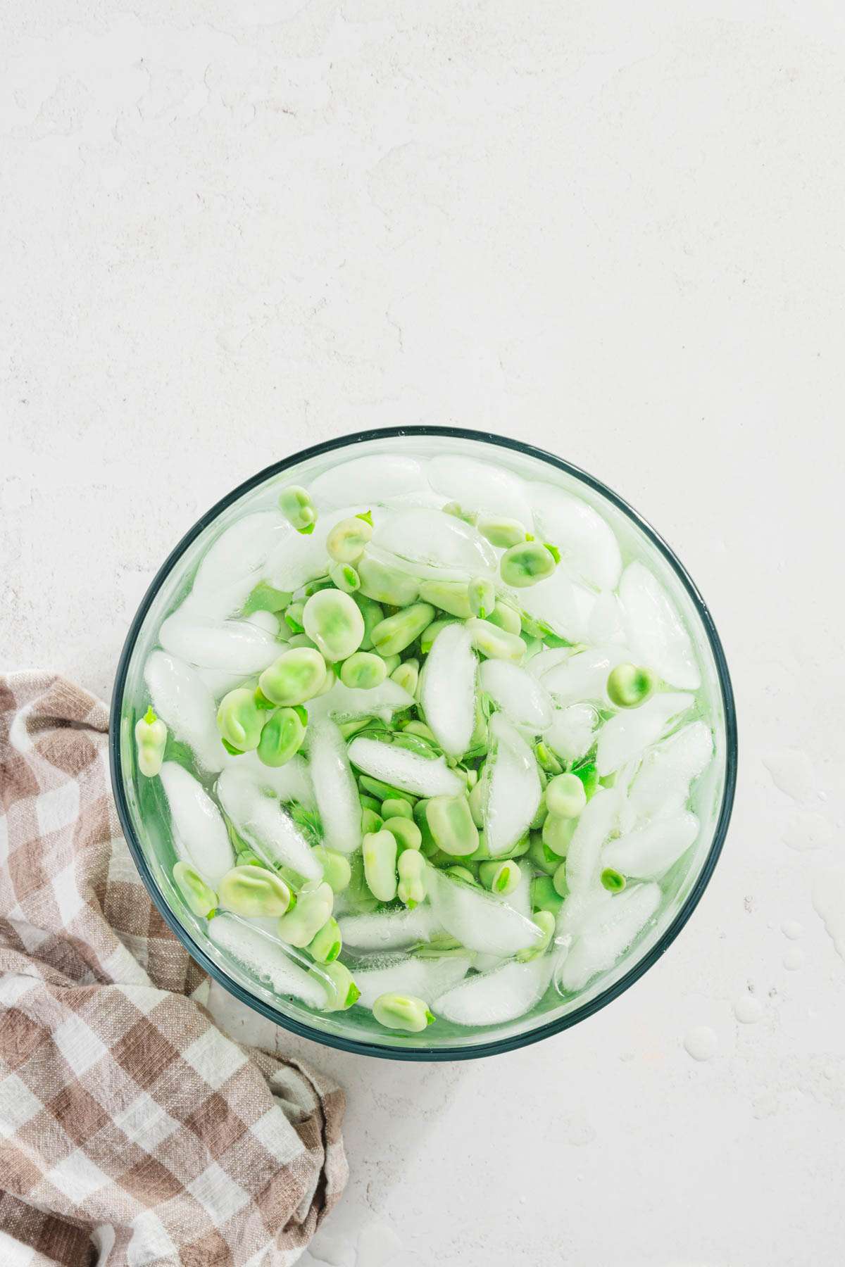 bowl with iced water and blanched fava beans added