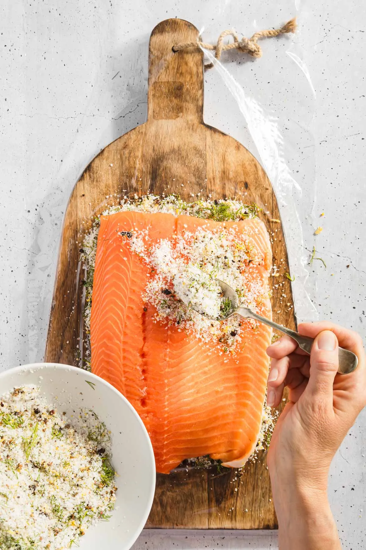 hands in frame applyin gcure to the raw salmon
