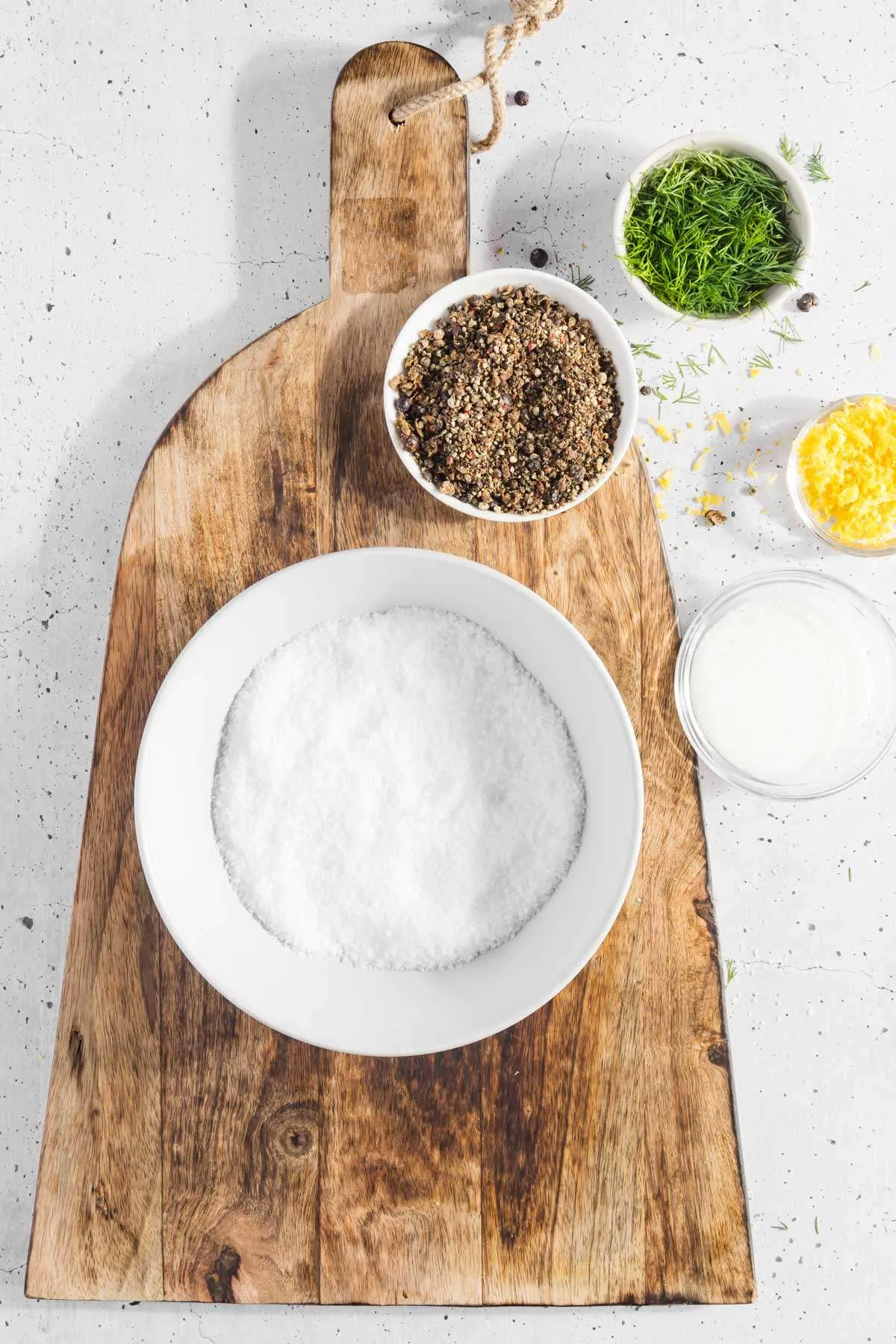 bowl with salt, other cure ingredients around, set on a wooden cutting board