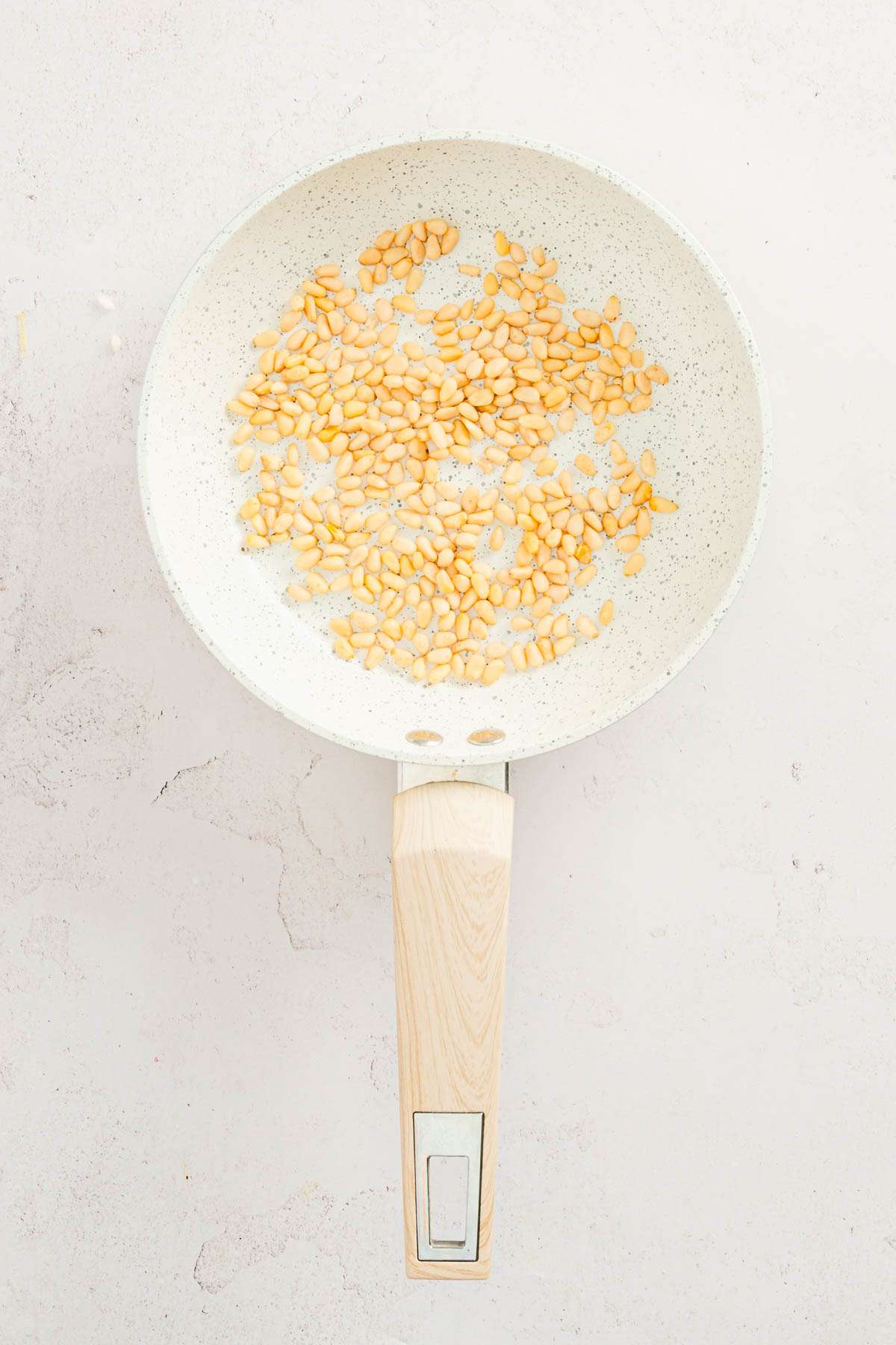 raw pine nuts on a frying pan