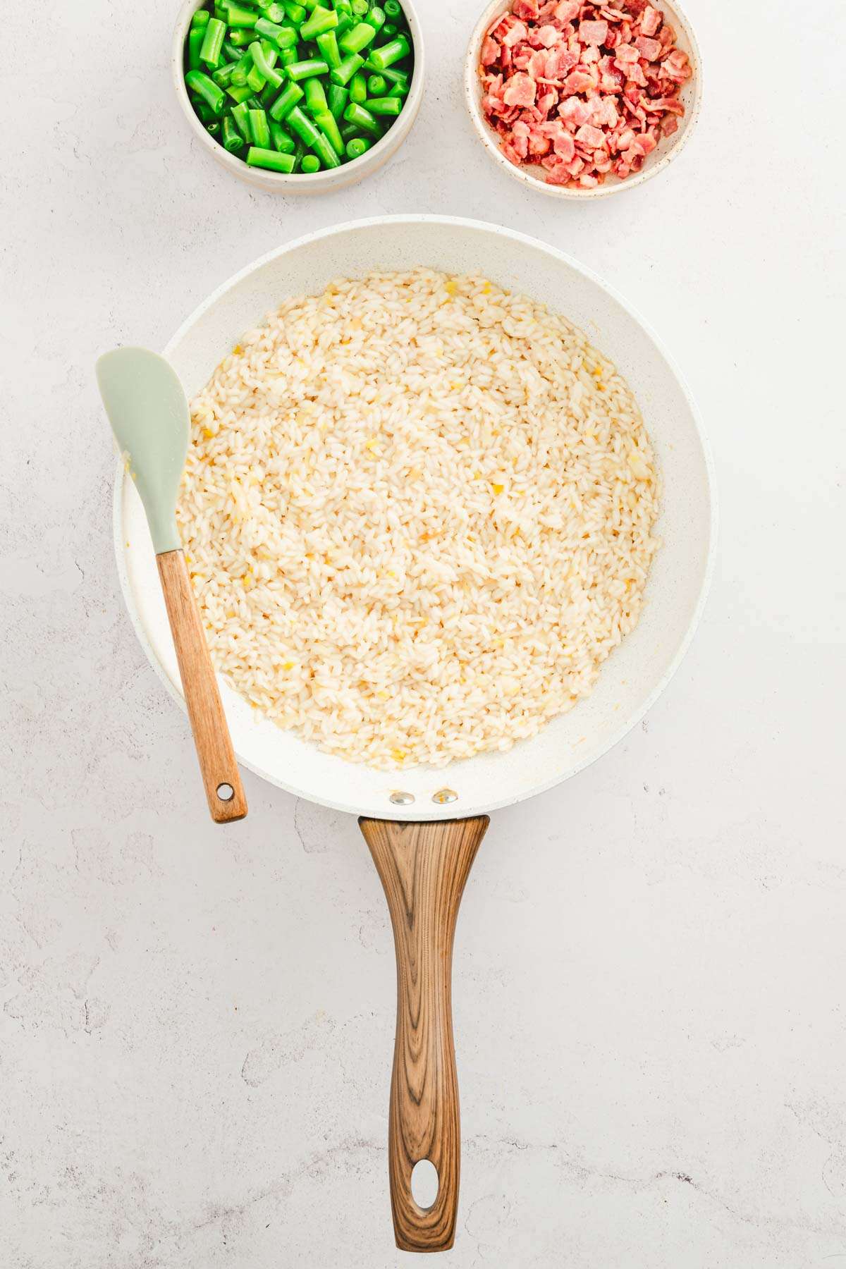 frying pan with rice, dishes with beans and bacon on the side