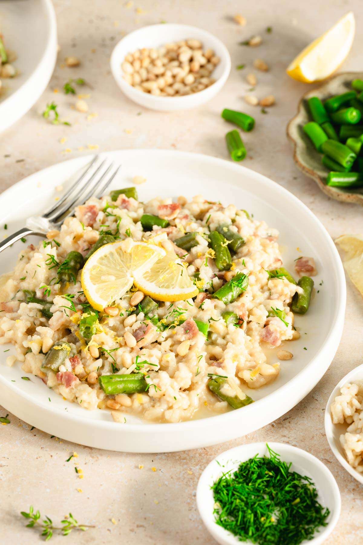 green bean risotto in a serving plate, side of green beans, pine nuts, fresh dill, close up