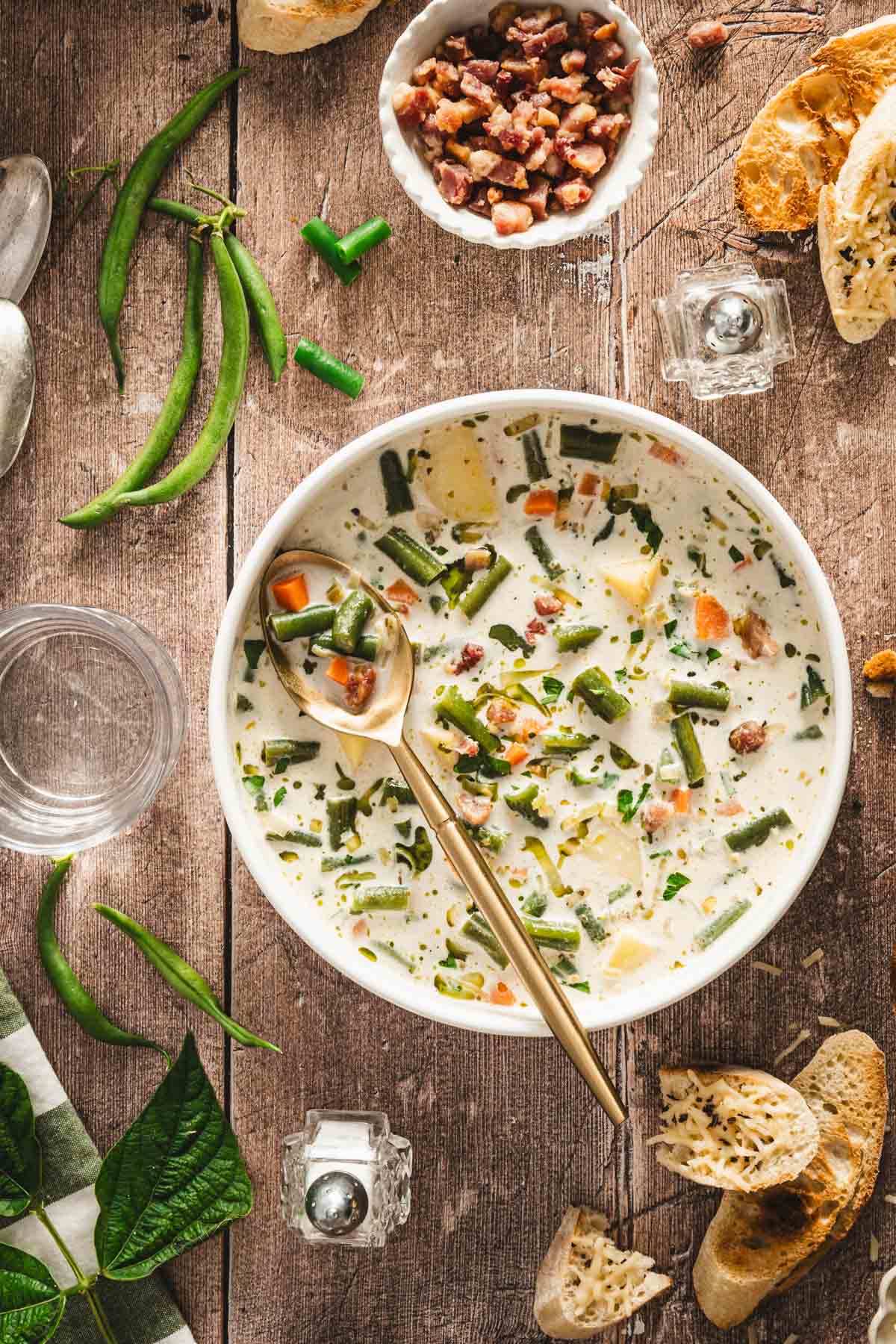 serving bowl with green bean soup, croutons, slices of bread