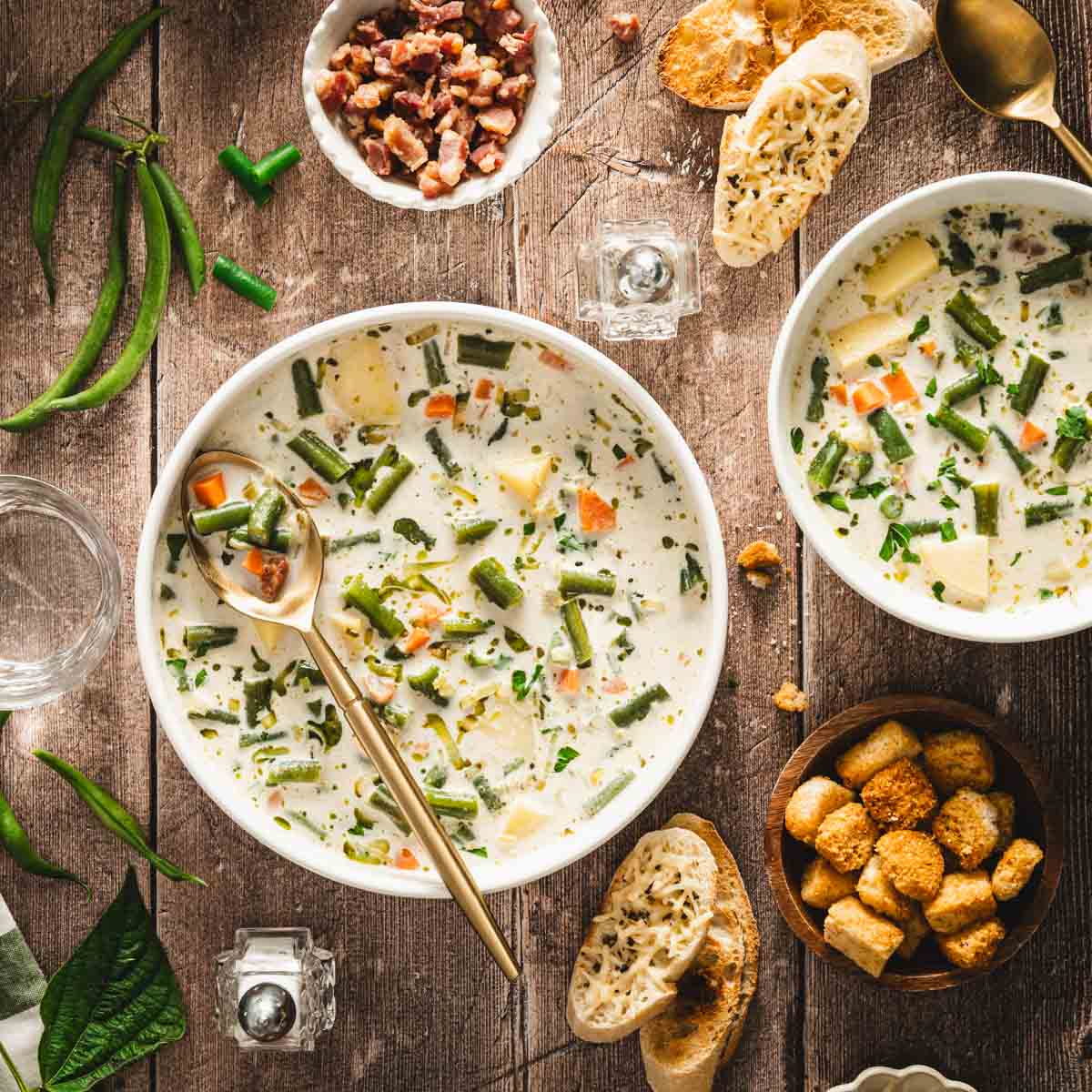 serving bowls with green bean soup, croutons, slices of bread