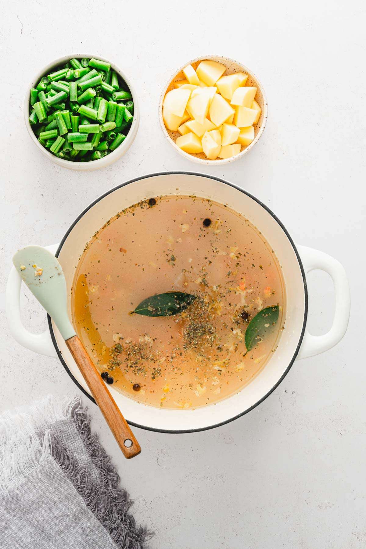 soup pan with broth and veggies cooked, dish with green beans and potatoes