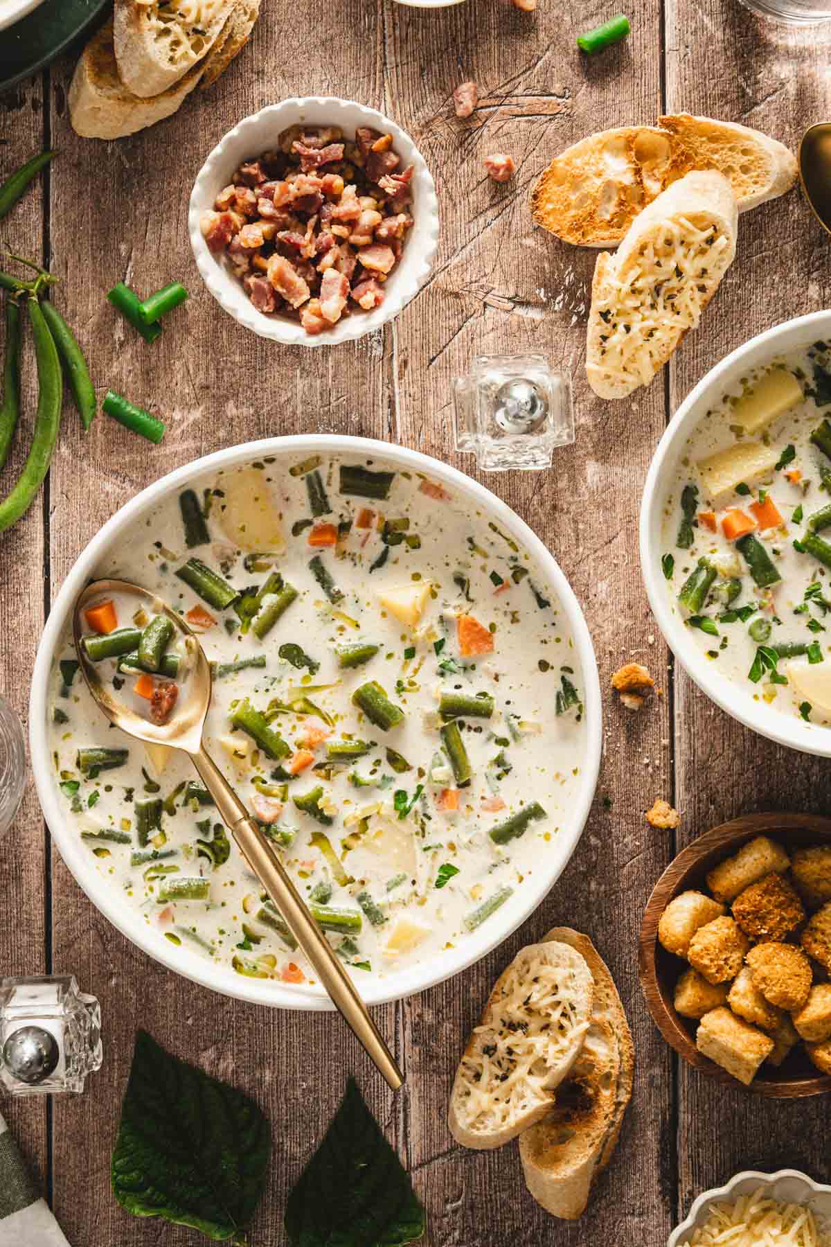 serving bowls with green bean soup, croutons, slices of bread