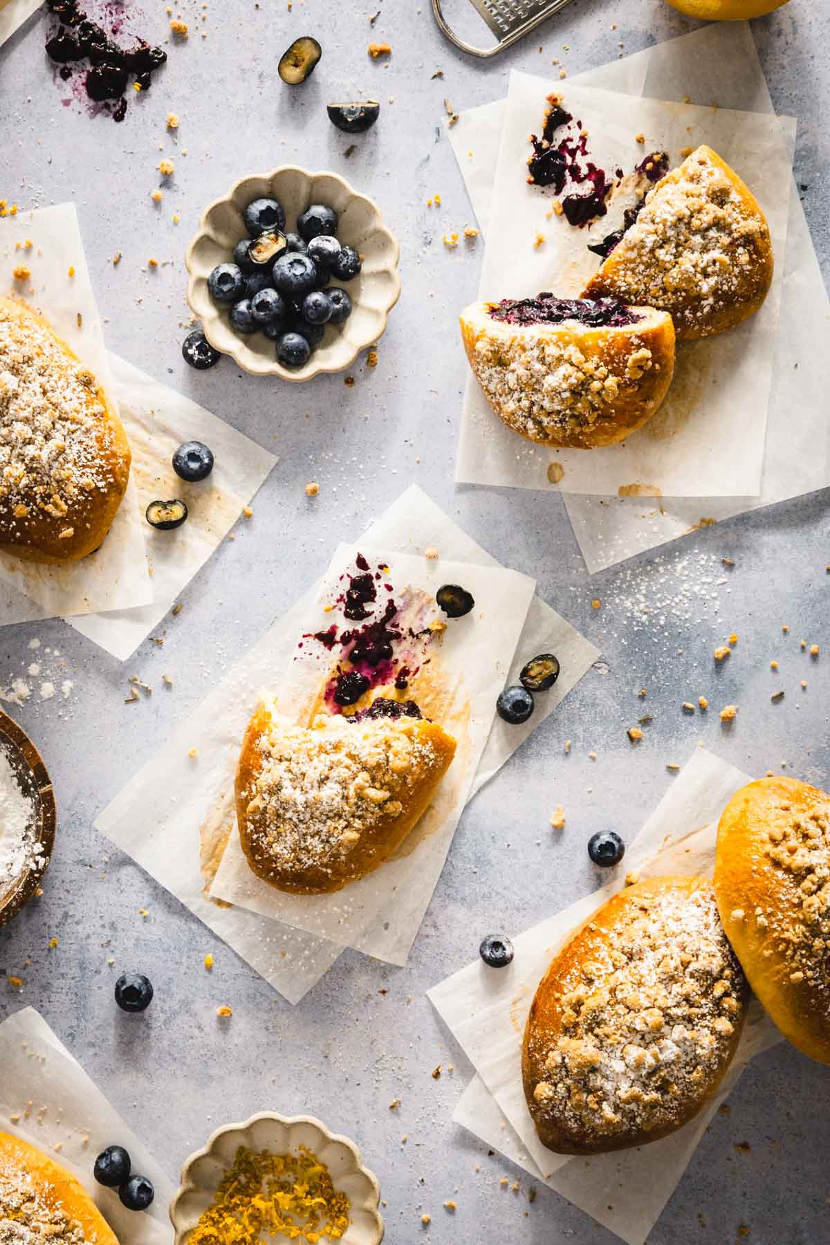 jagodzianki on a blue surface and cut out parchment paper, small dish with blueberries