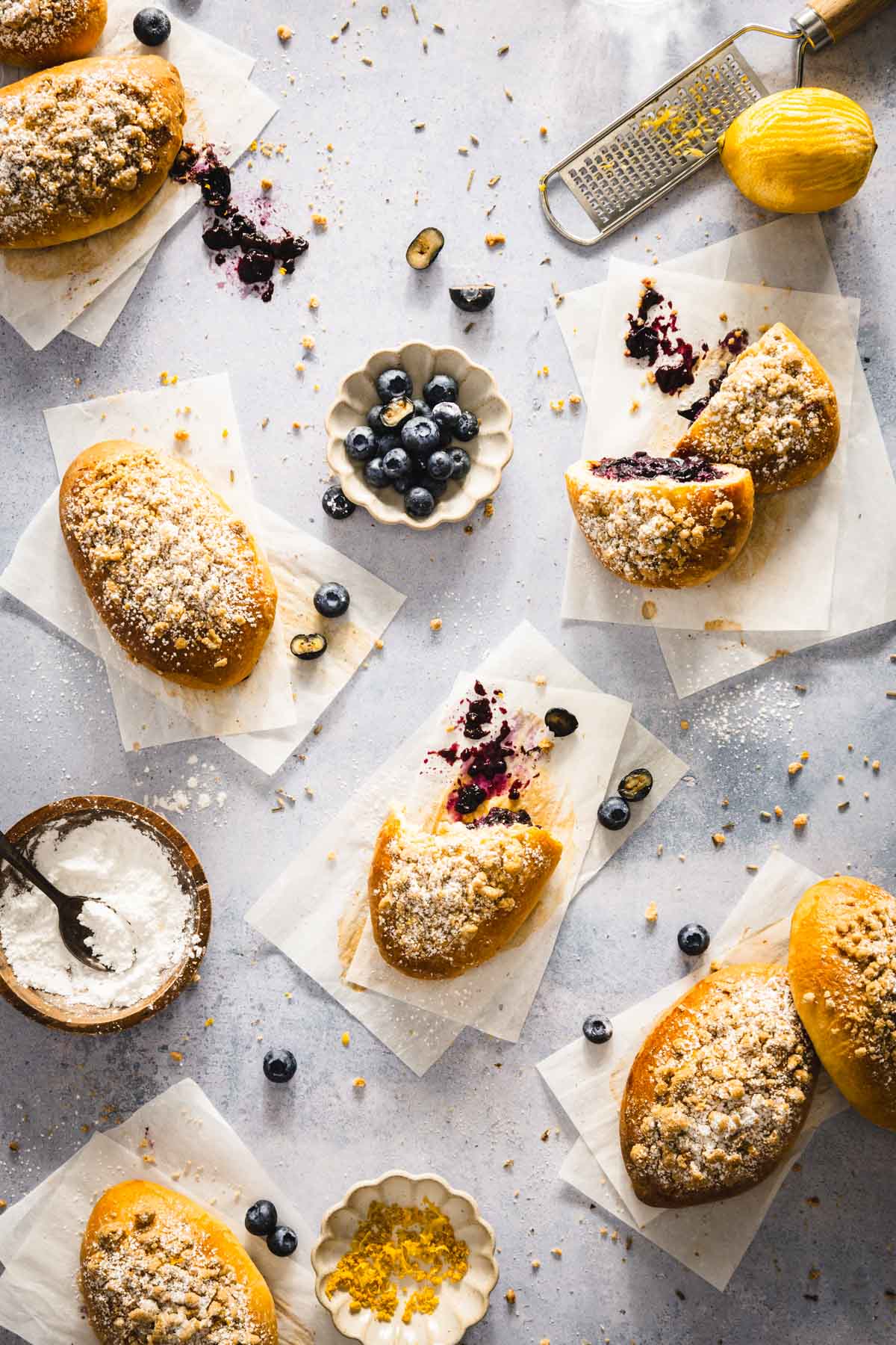 jagodzianki on a blue surface and cut out parchment paper, small dish with blueberries