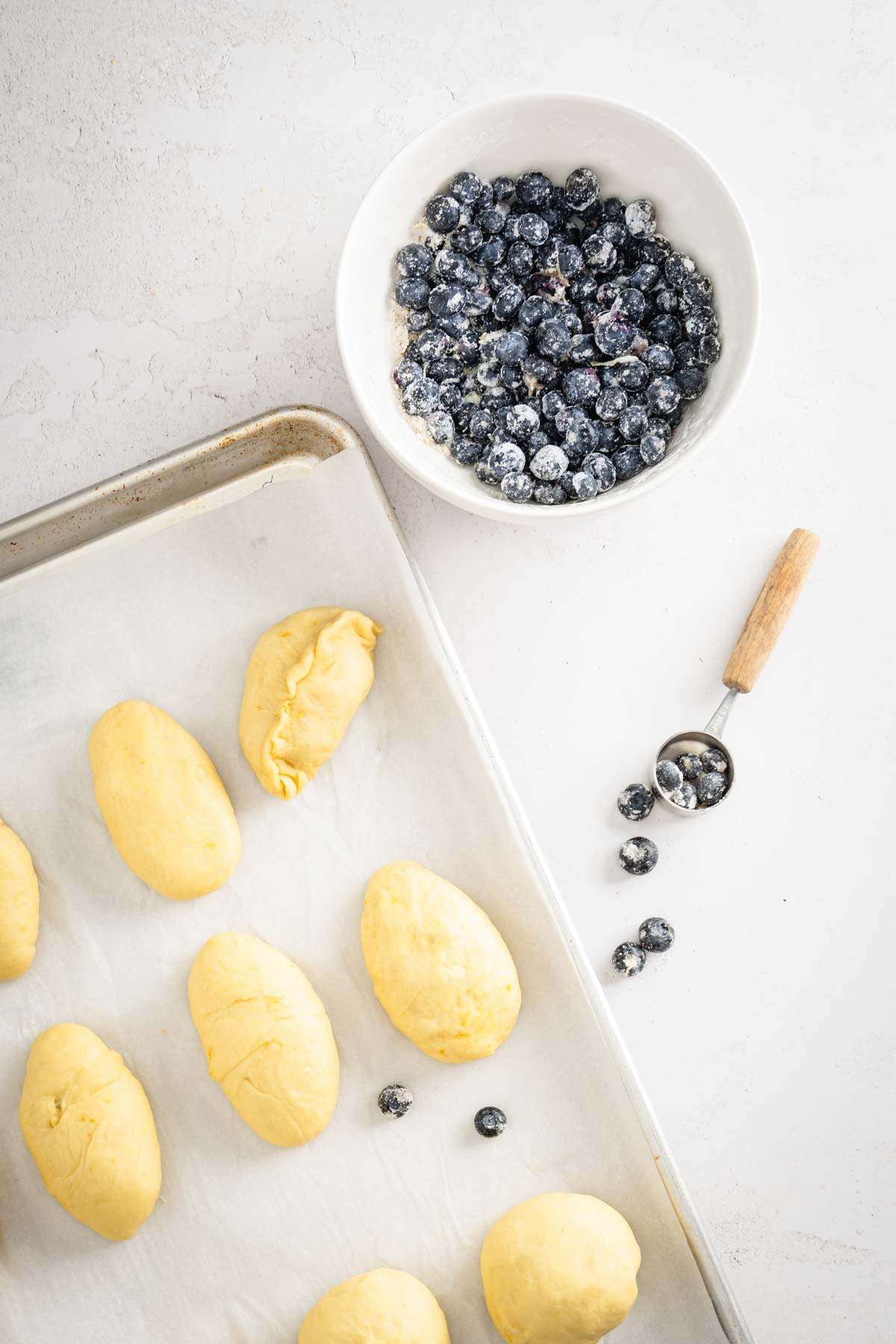 jagodzianki dough, bowl with blueberries, measuring spoon