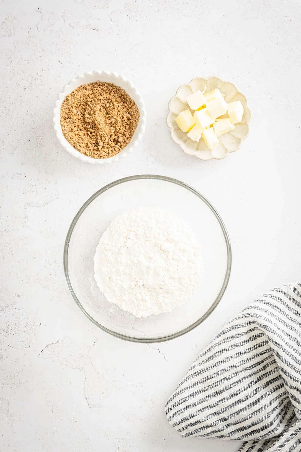 glass bowl with flour, dish with brown sugar, one with butter