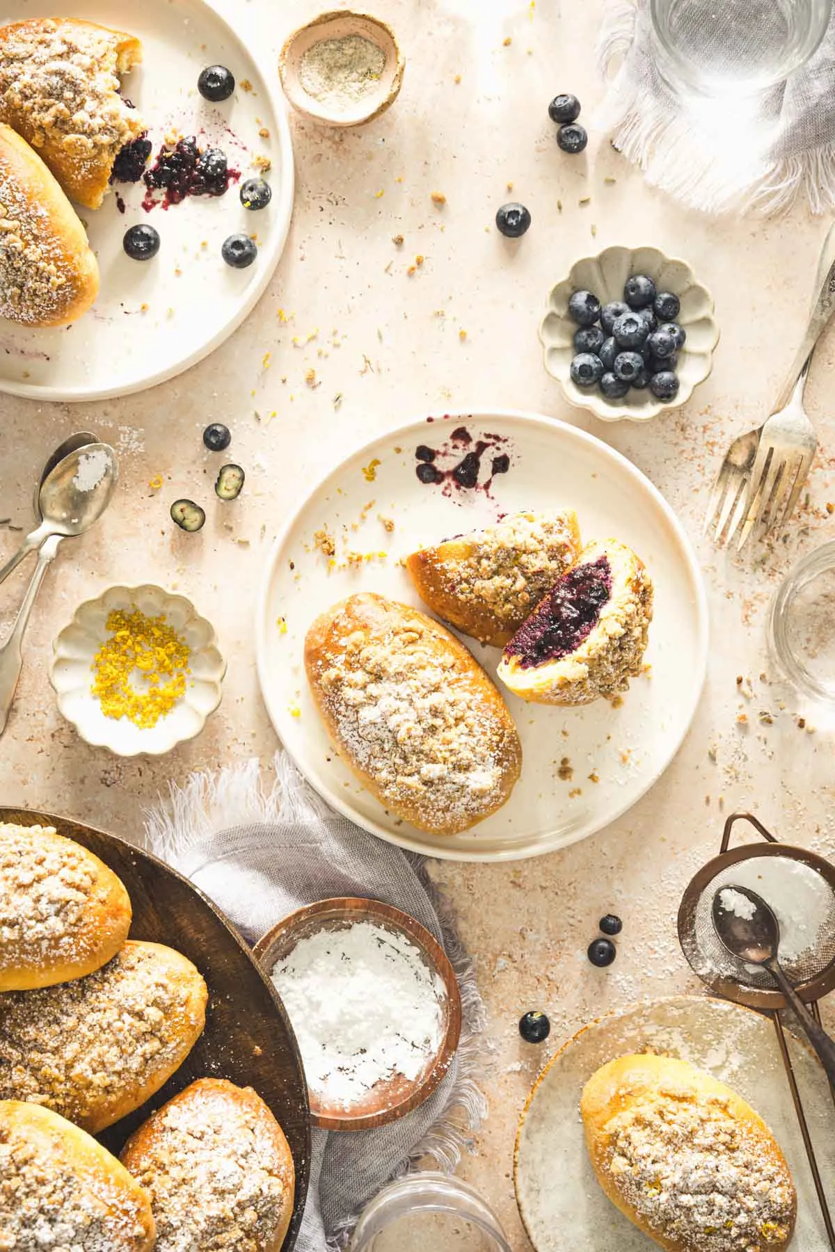 jagodzianki on a serving plate, dish with fresh blueberries and lemon zest, cake stand with more jagodzianki
