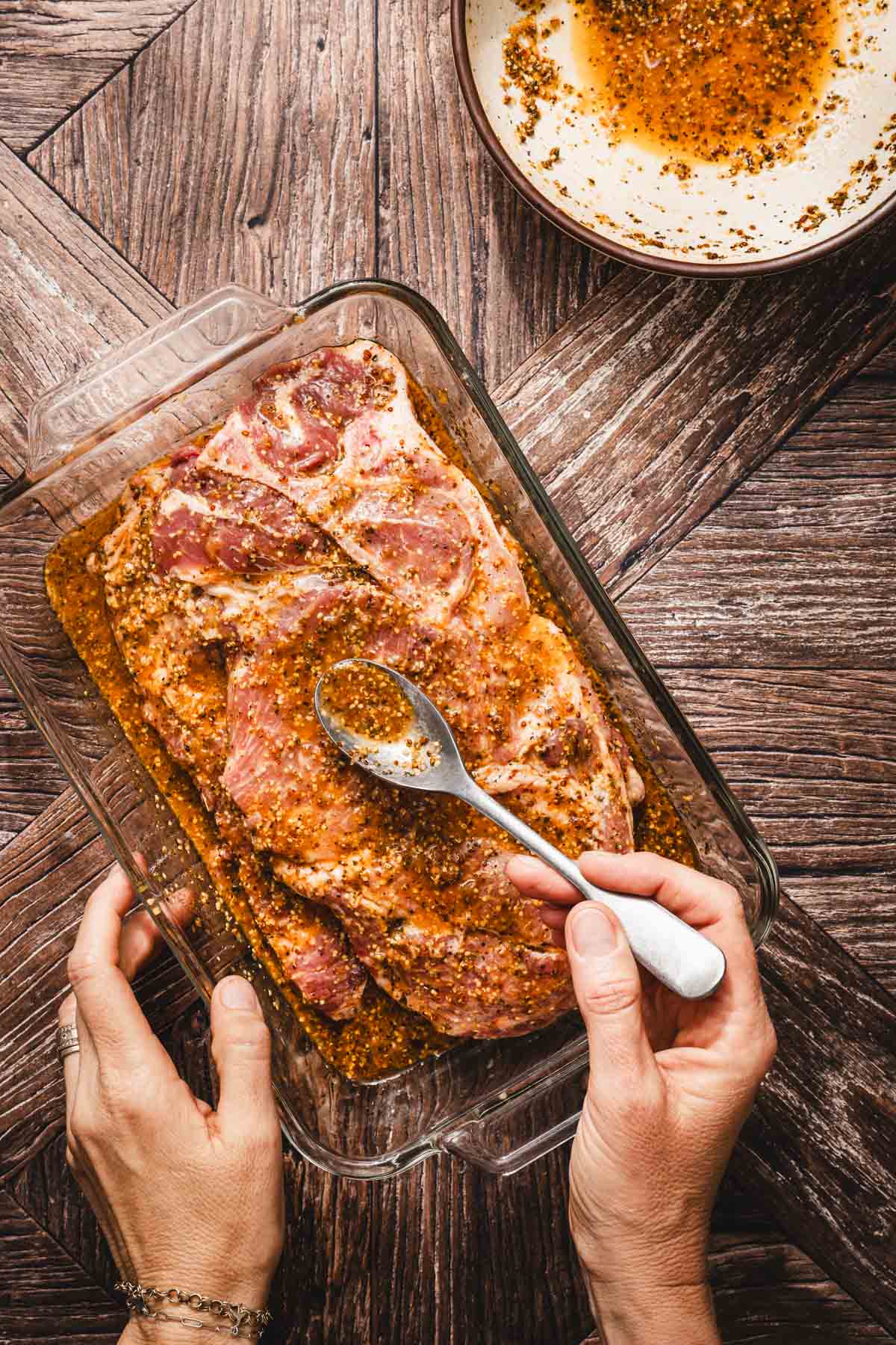 hands in frame applying marinade to the meat