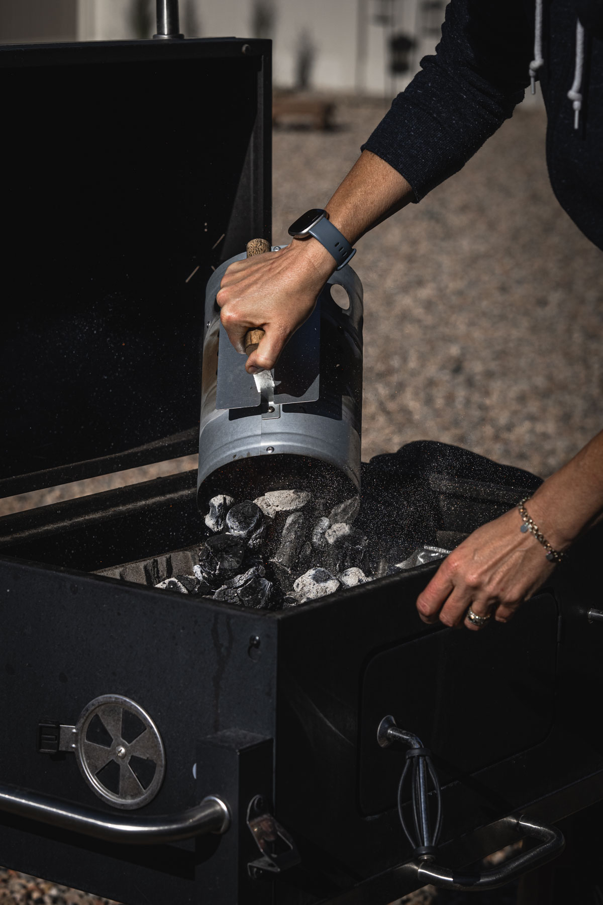 hands in frame holding grill chimney dumpig coals