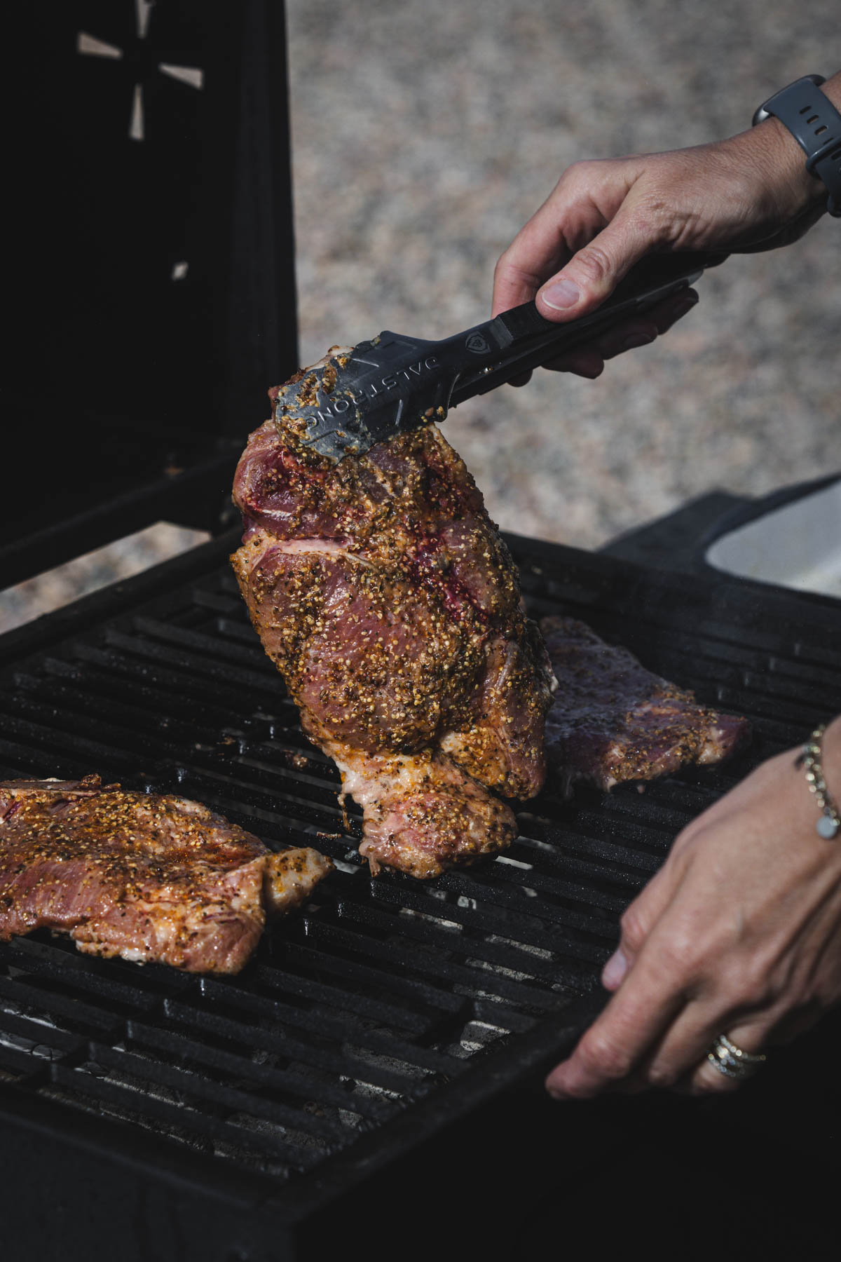 hands in frame holding tongs and piece of karkowka meat
