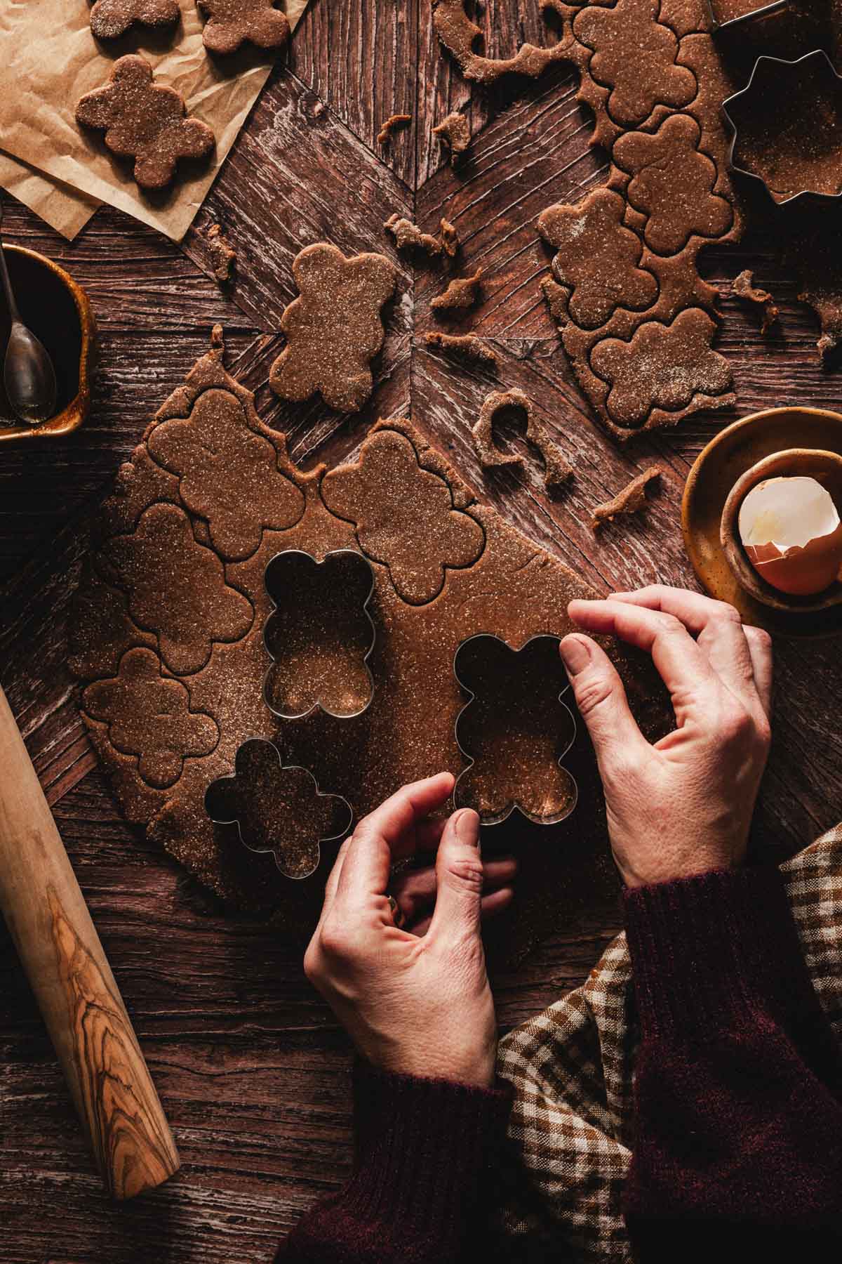 hands in frame holding cookie cutters over the rolled out dougg