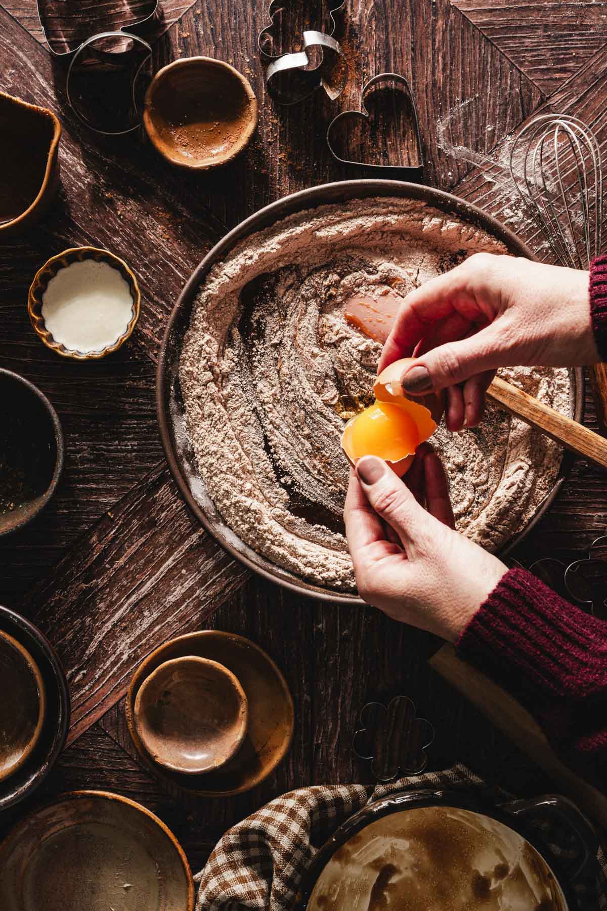 hands in frame adding an egg to the batter