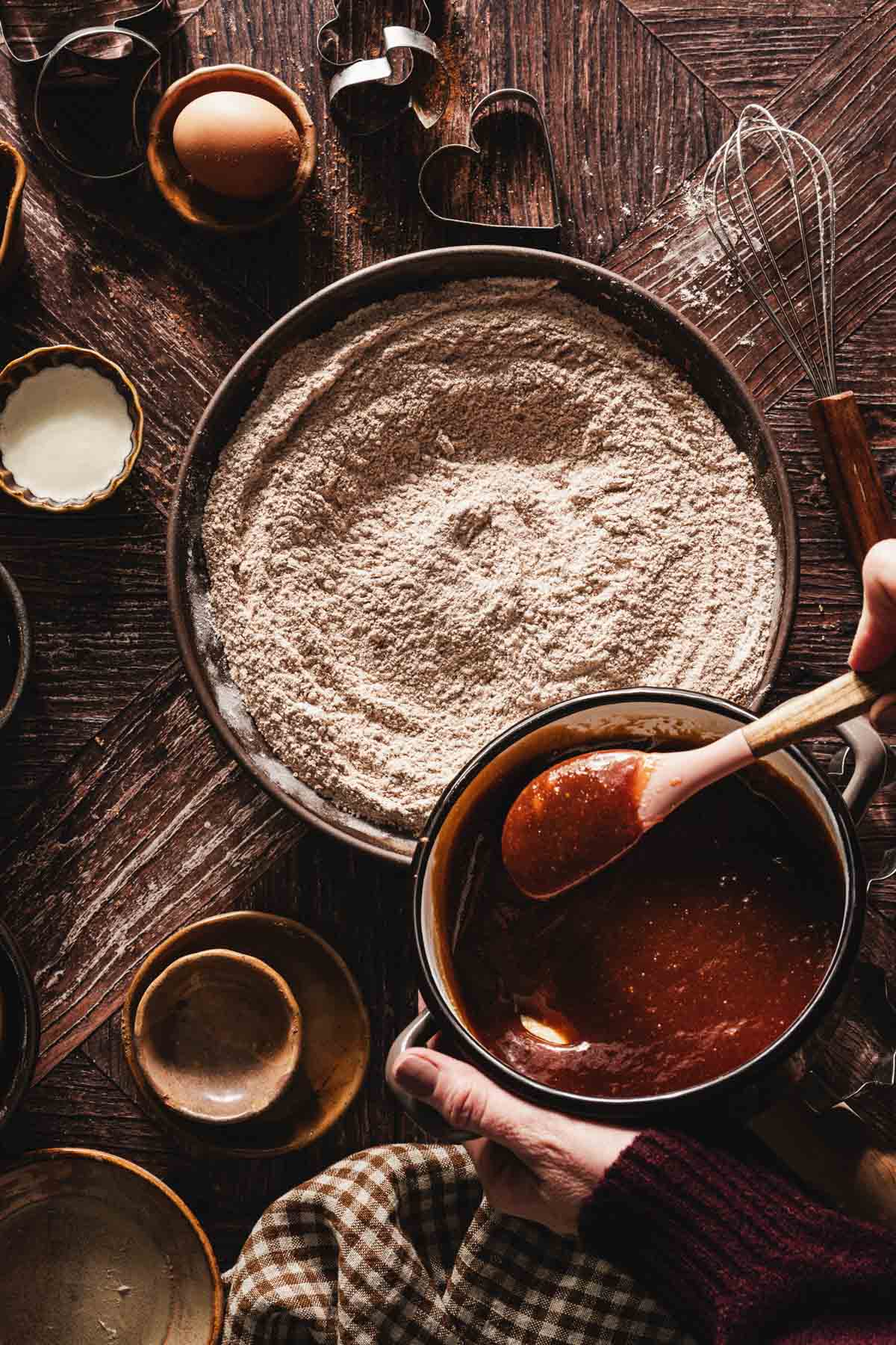 hands in frame pouring honey mixture to the flour mix