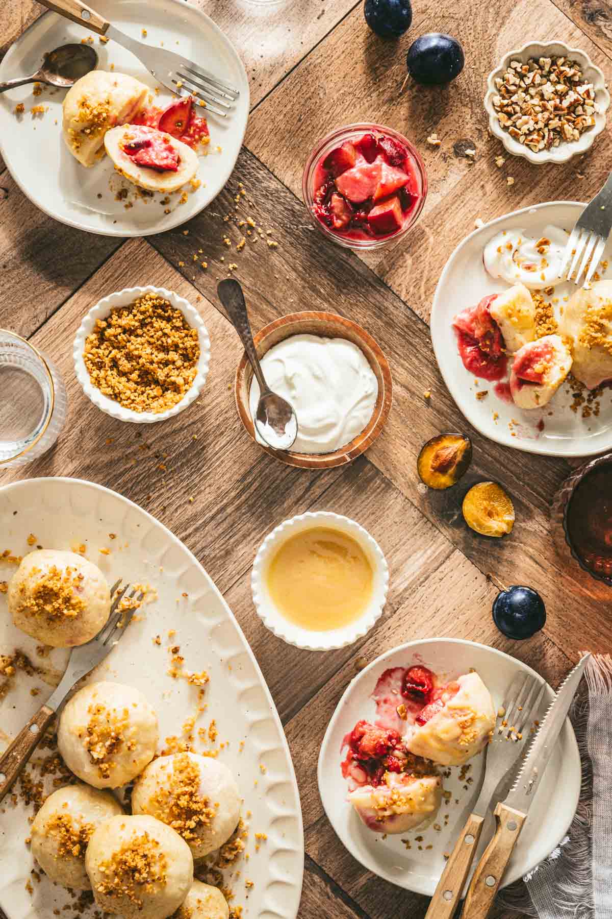 knedle ze sliwkami on a serving plates, dish with breadcrumbs, cream, cooked plums, brown butter