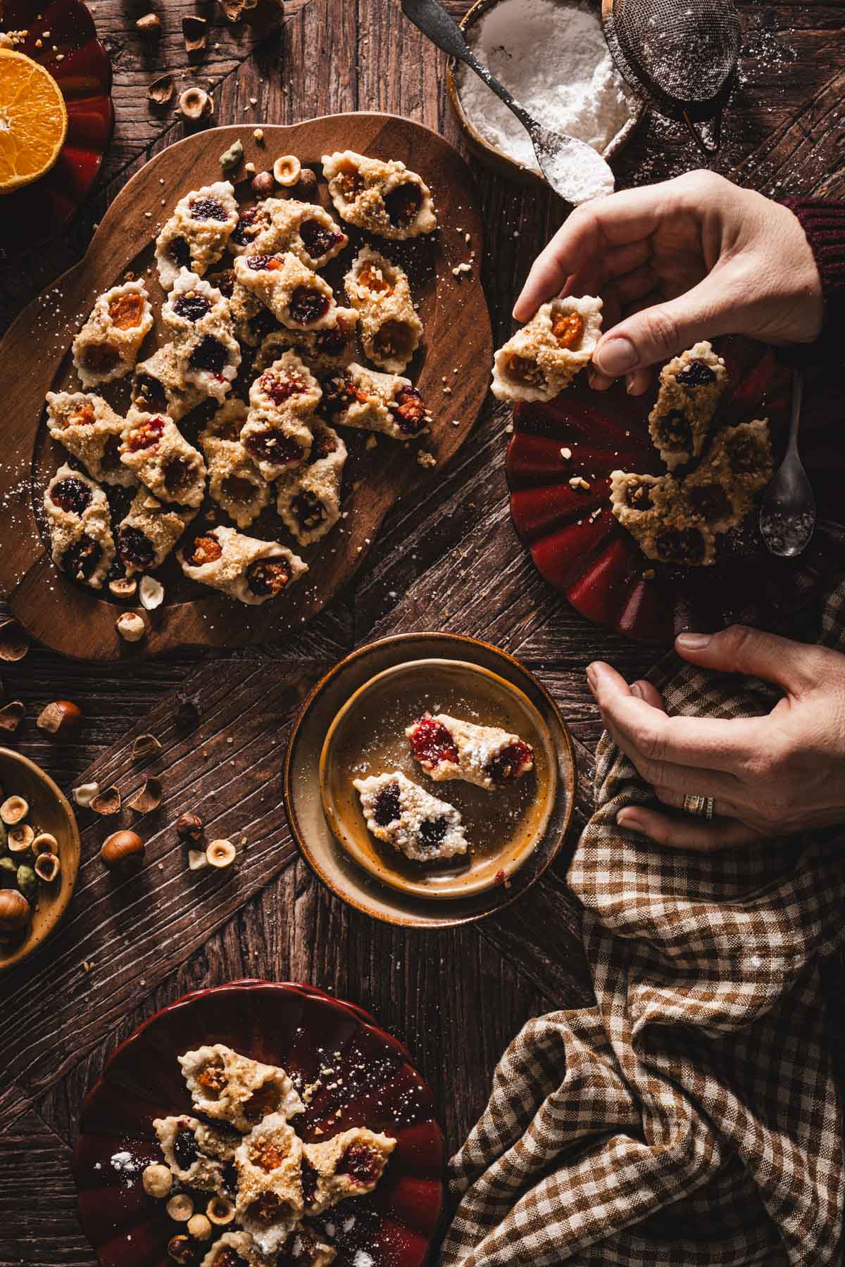 hands in frmae holding kolaczki cooki,other plates with cookies