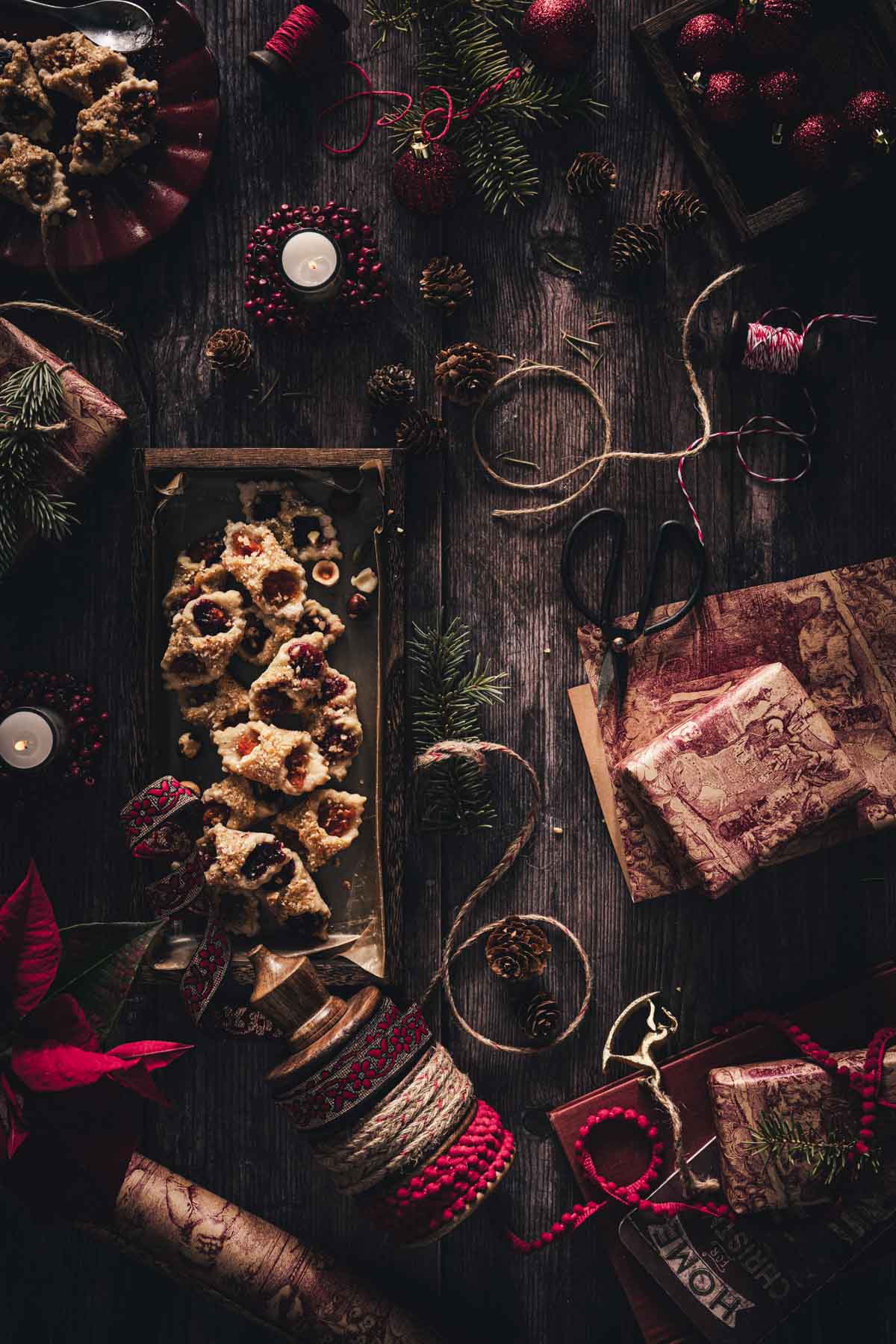 kolaczki cookies in a serving wooden tray, candle, festive ribbons, pine branches, boxes with gifts