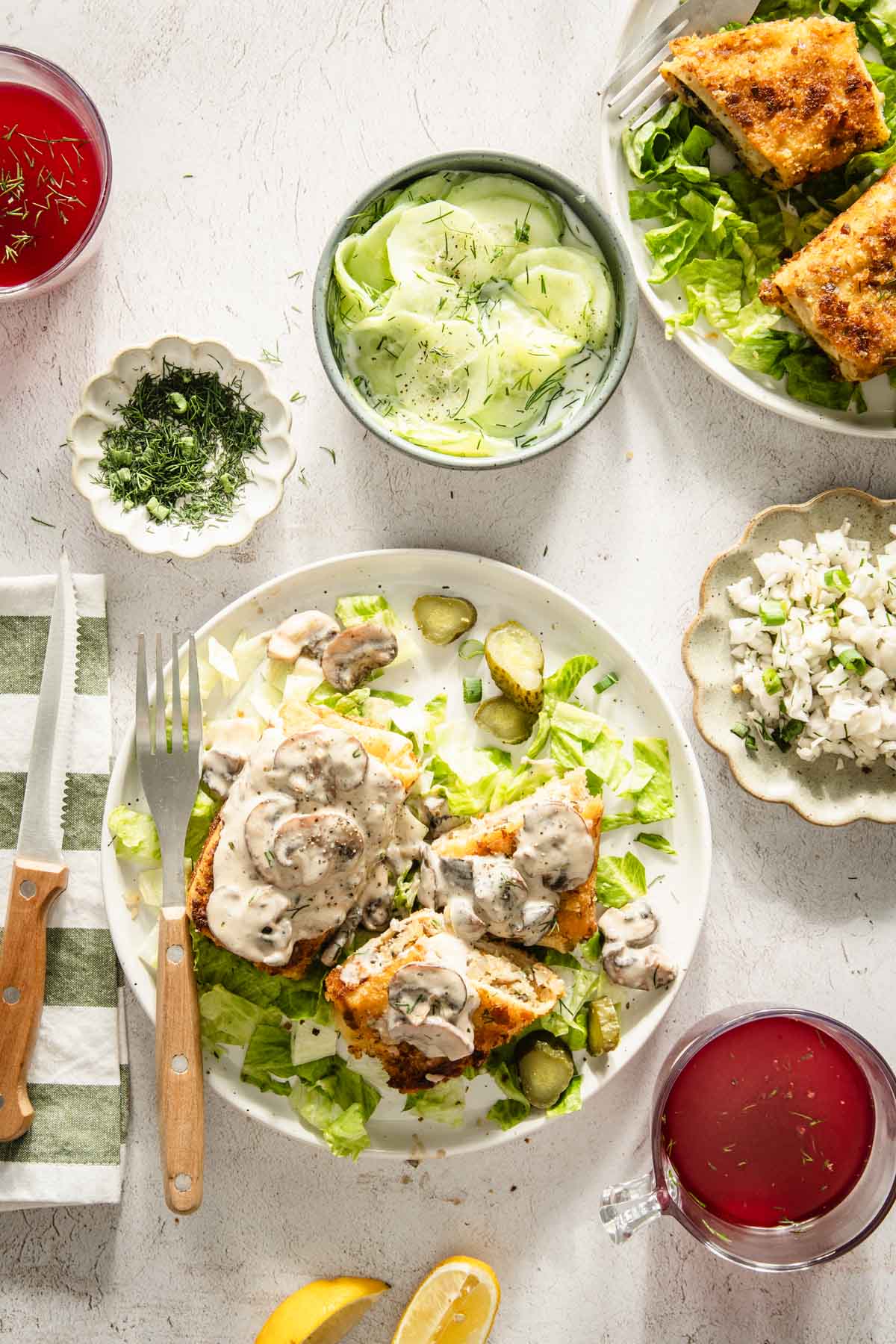 krokiety served on a plate with mushroom sauce, various salads, utensils to eat, glasses with red borsht