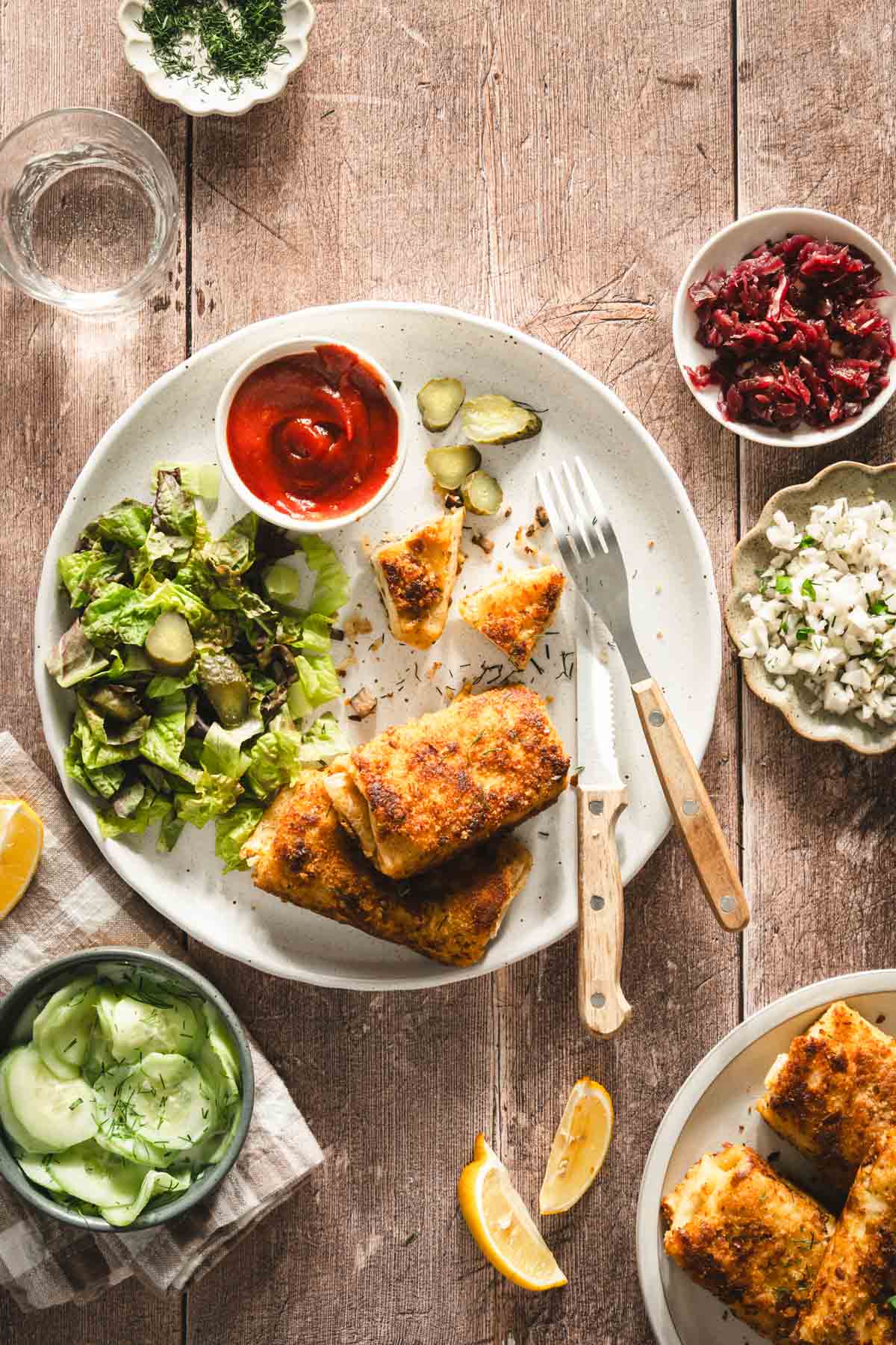 krokiety served on a plate, with salad and ketchup; dish with cabbage salad, beet salad and sliced cucumbers