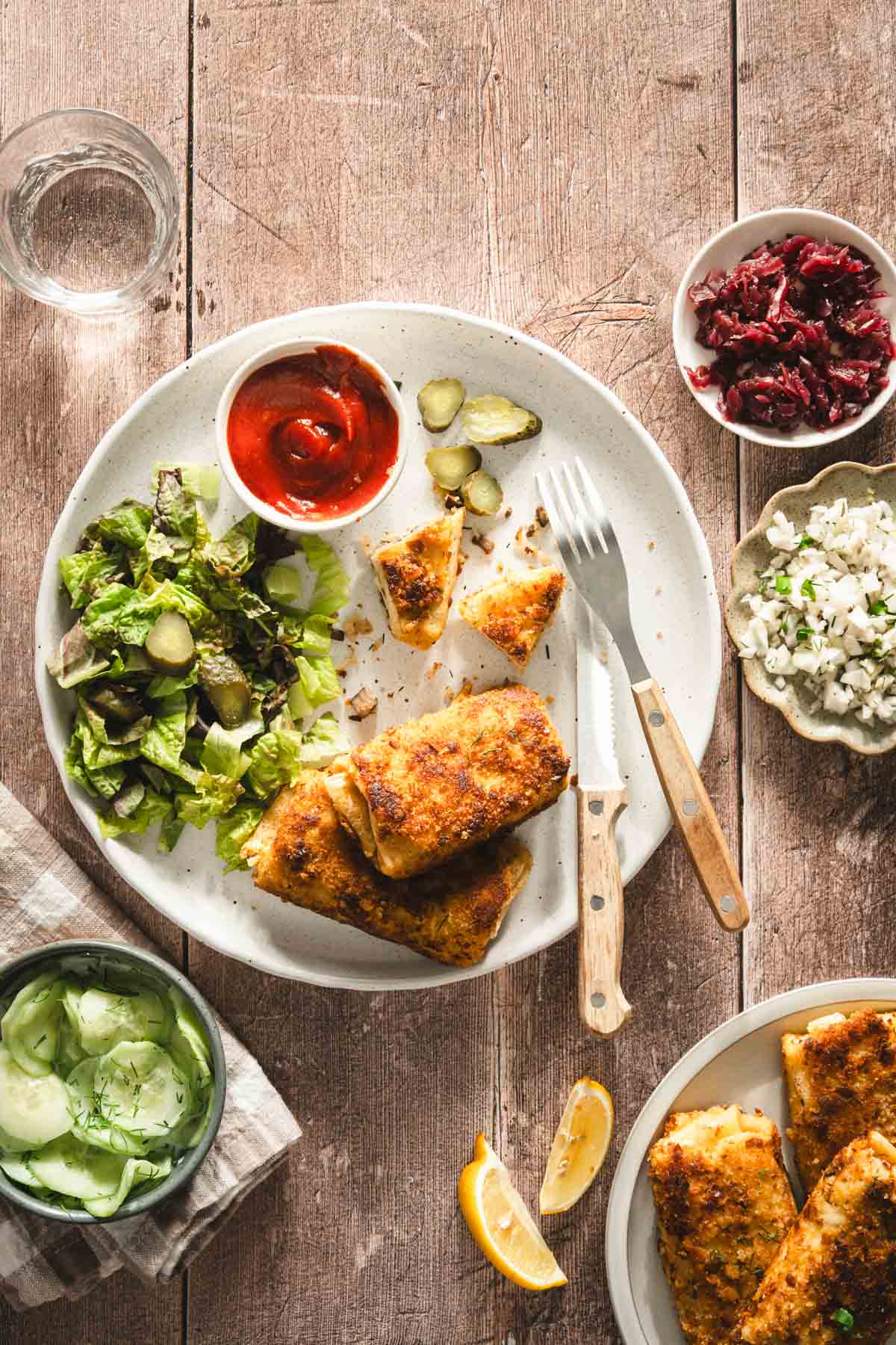 krokiety served on a plate, with salad and ketchup; dish with cabbage salad, beet salad and sliced cucumbers