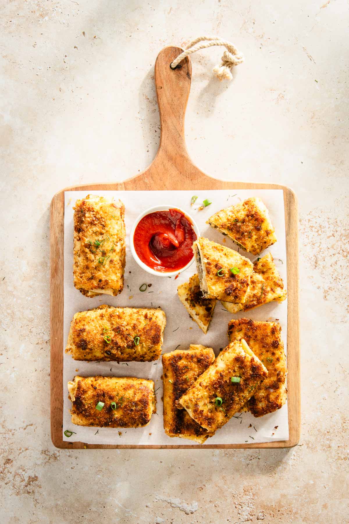 cooked krokiety on a cutting board with a ketchup for dipping