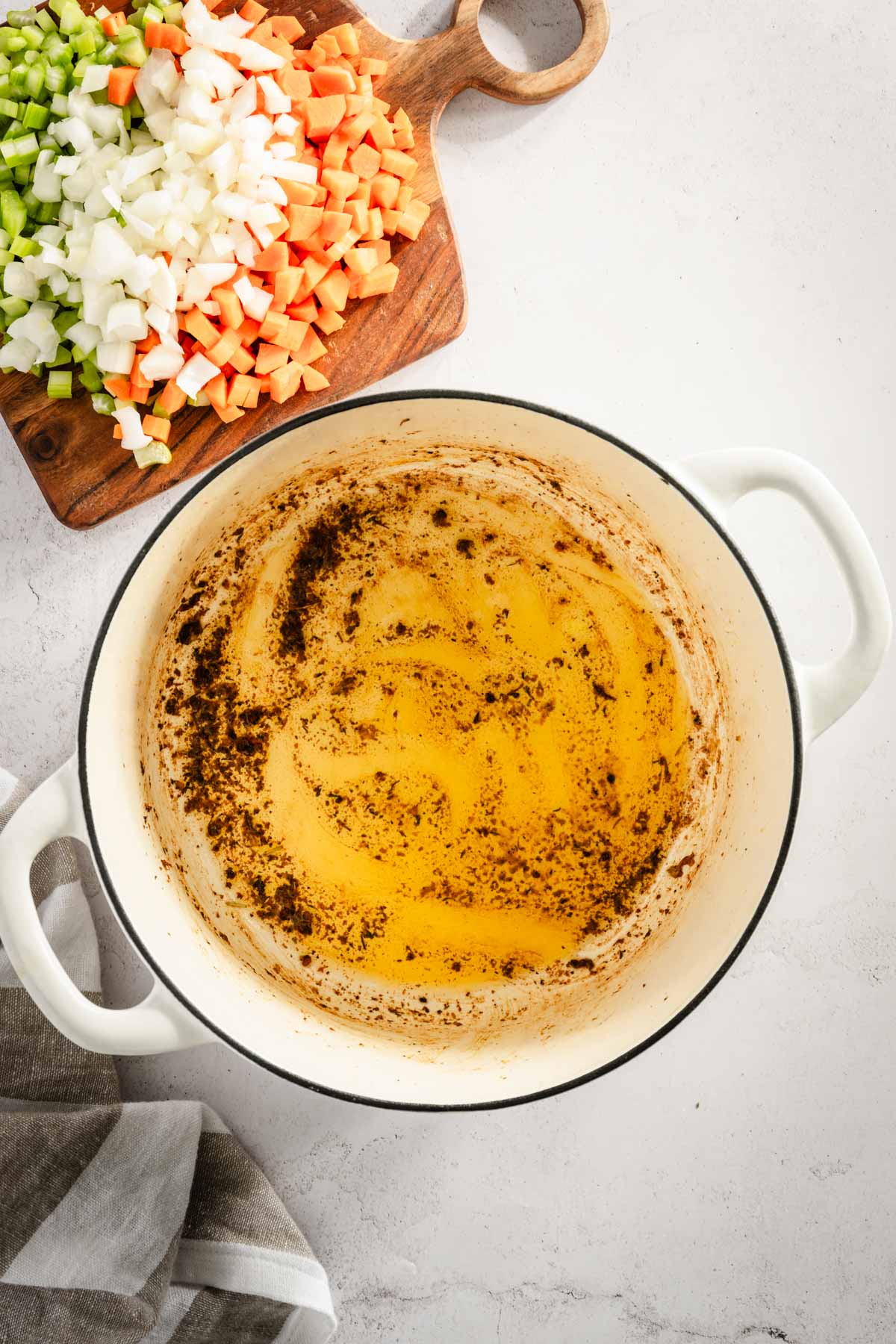 cooking pot with left over grease from cooking chicken, cutting board with veggies