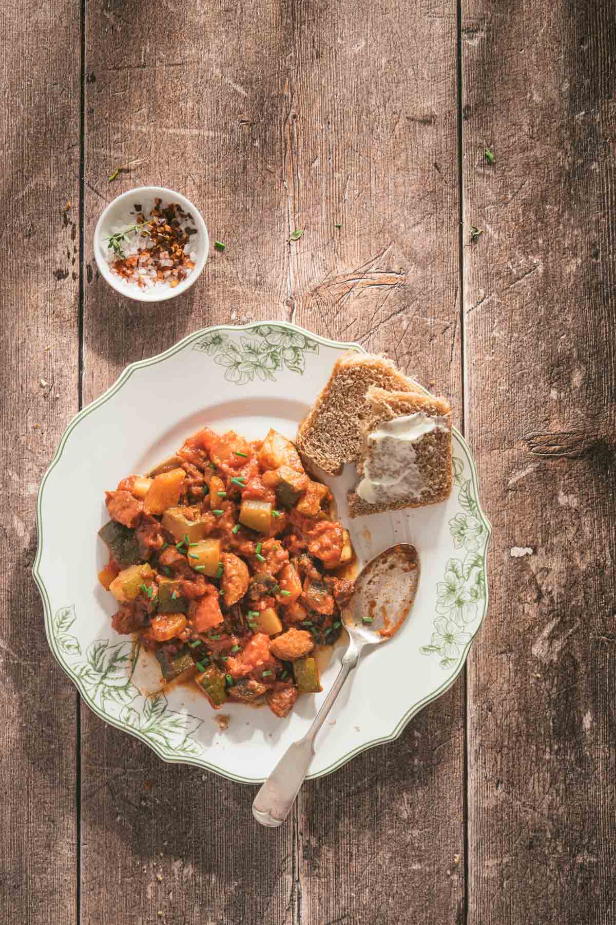 leczo on a serving plate, slices of bread, spoon