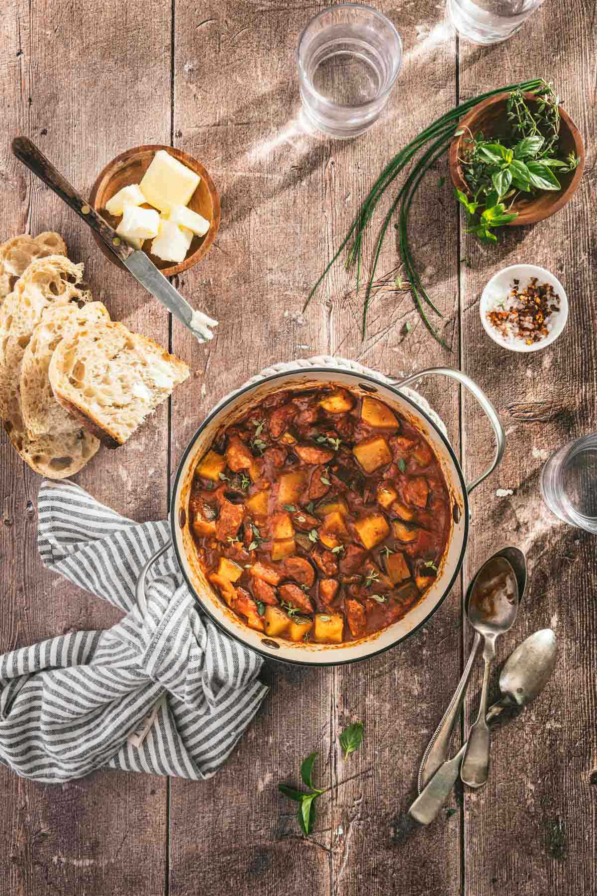 leczo in a pan, napkin, slices of bread, fresh herbs, spoons