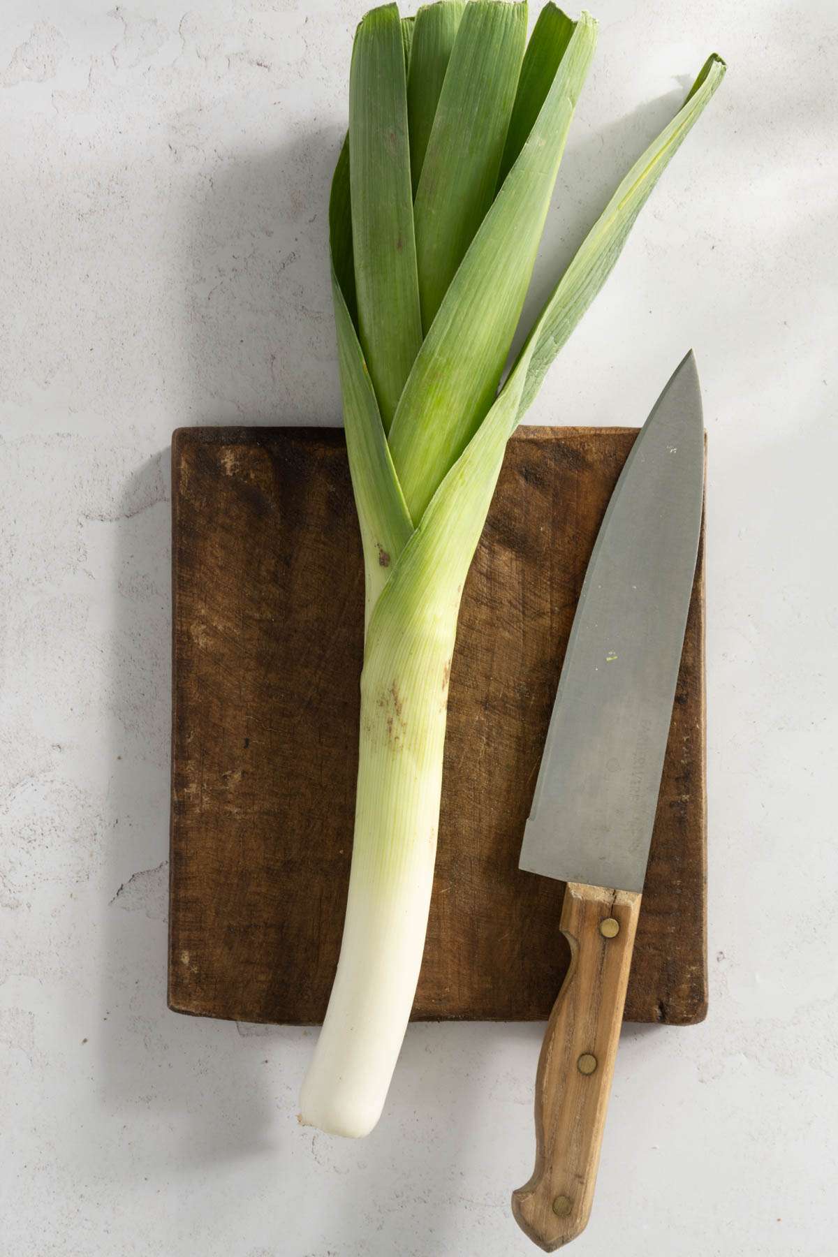 leek o a cutting board, large knife on the side