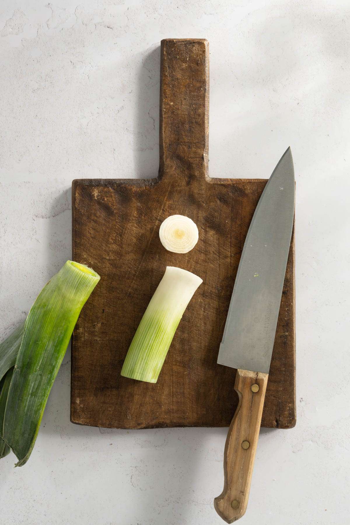 leek o a cutting board, with the end and green part cut off, knife on the side