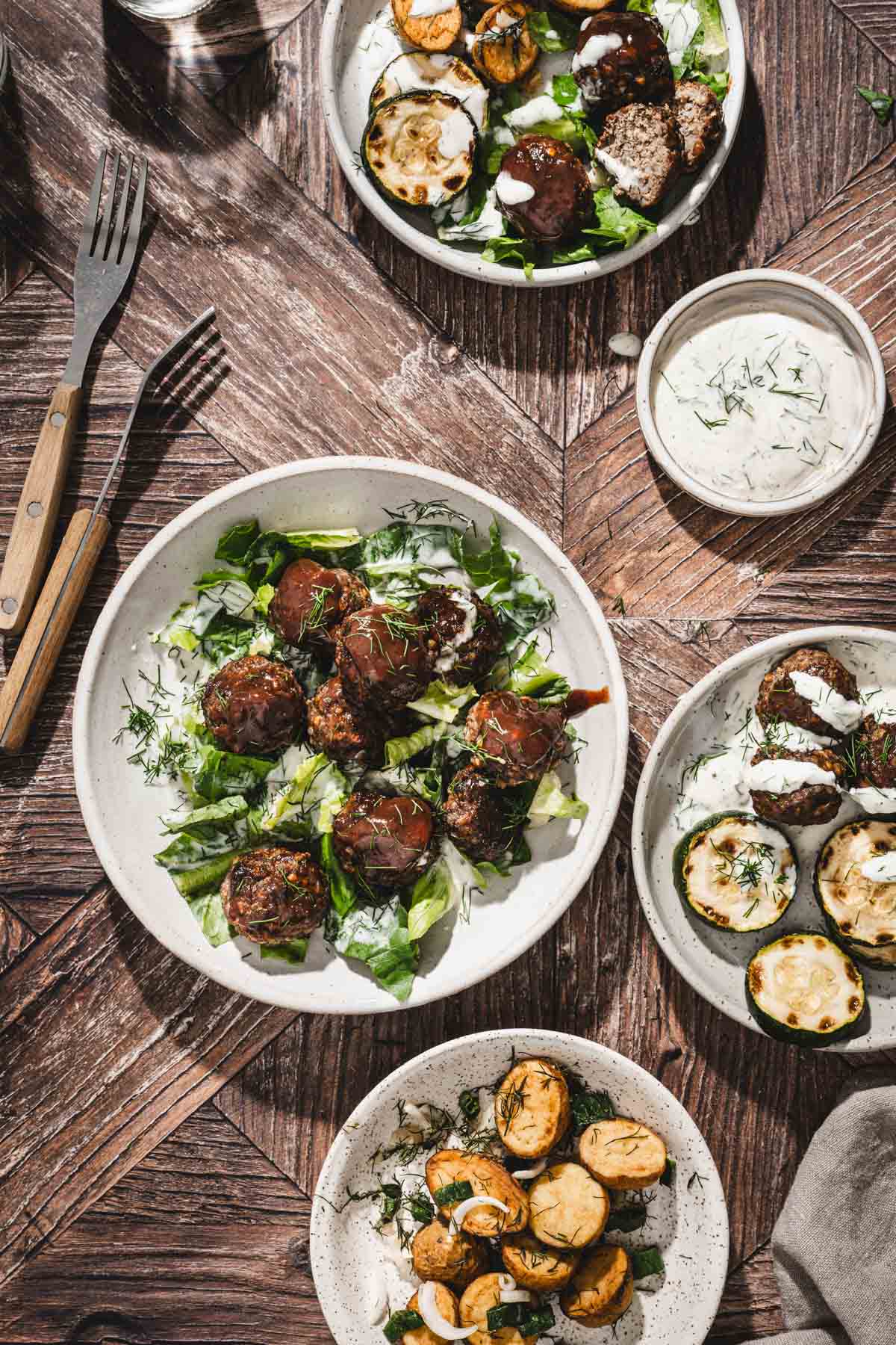 various plates with meatballs, salad, potatoes