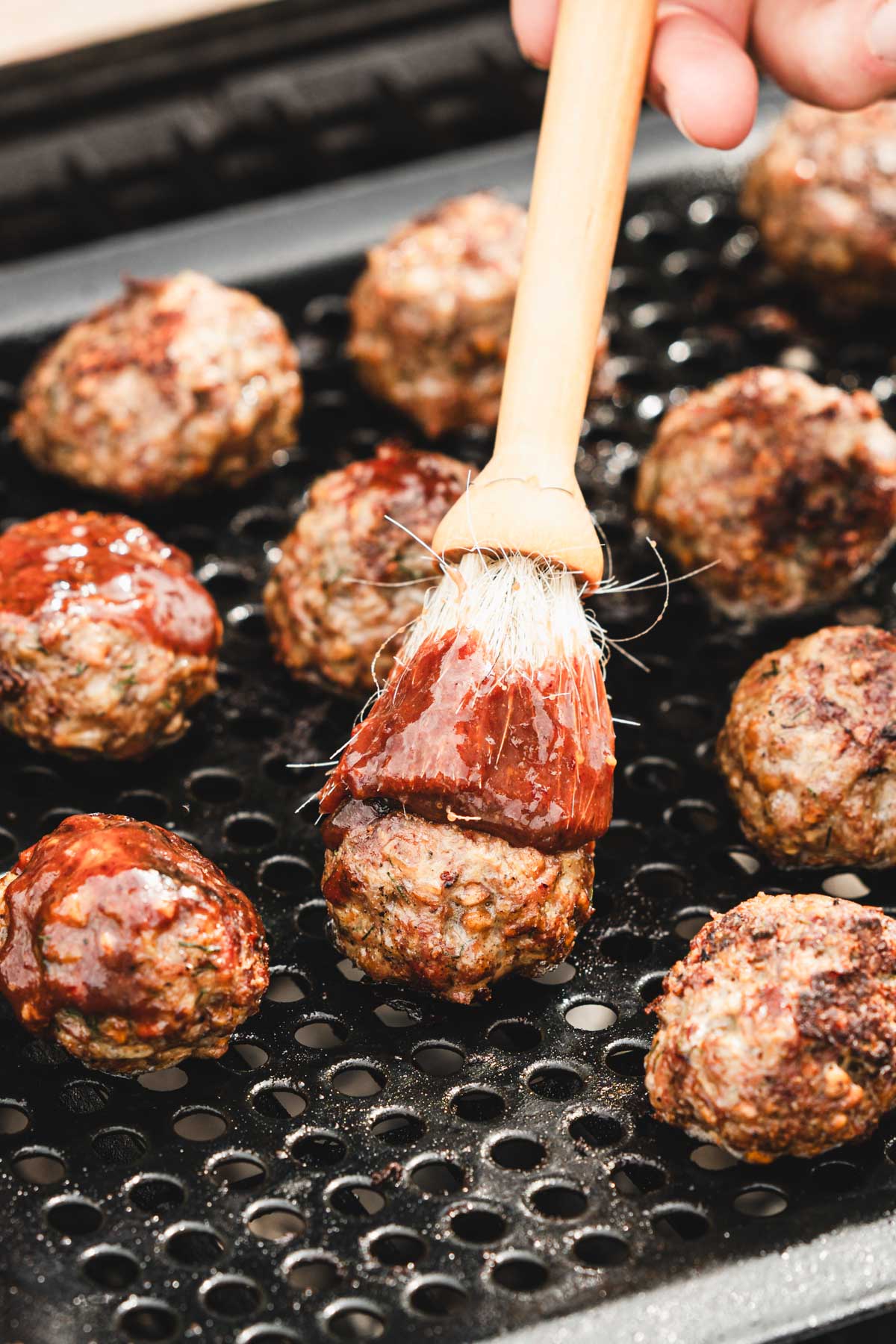 brushing meatballs while on the grill