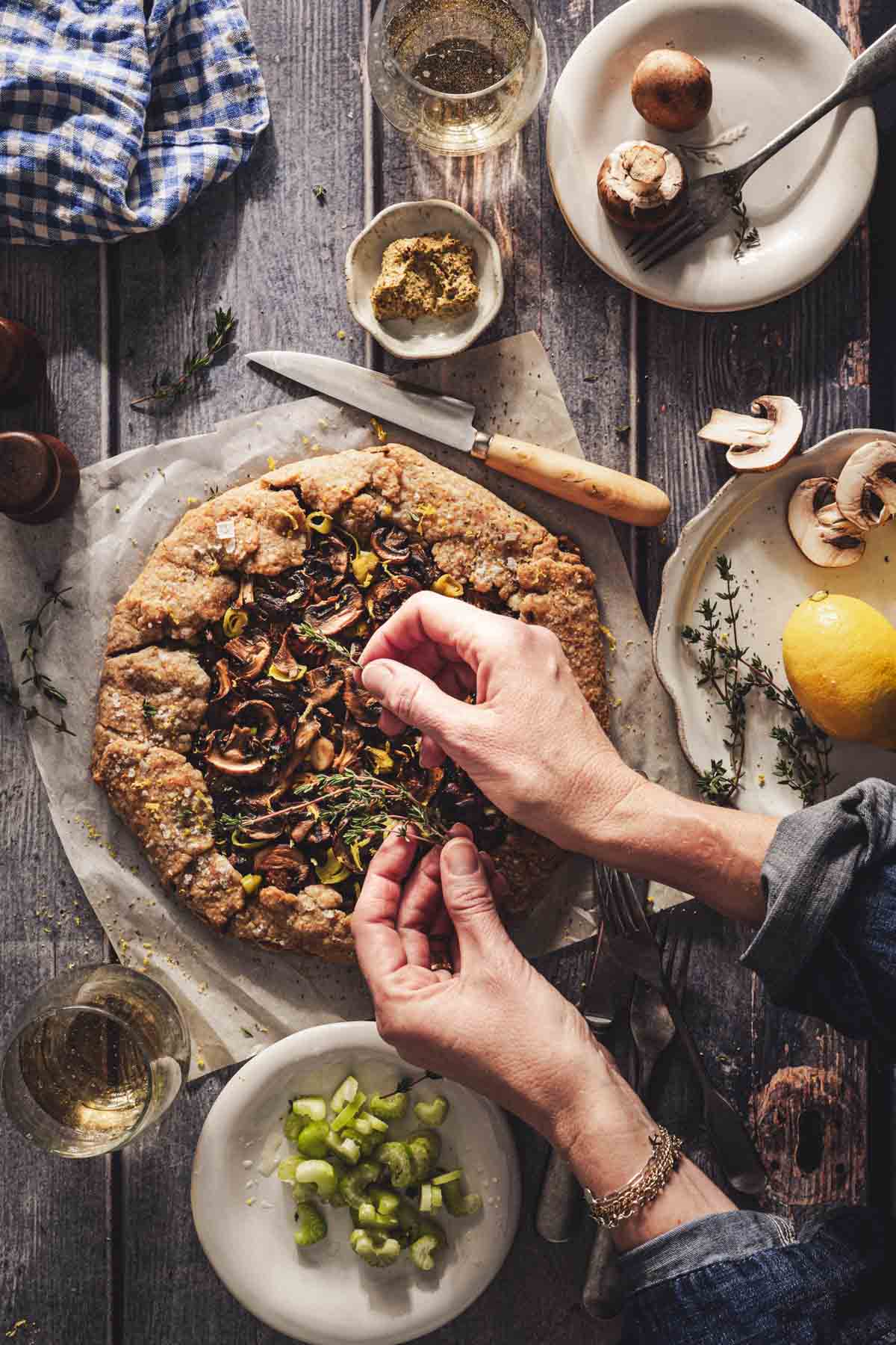 hands in frame adding thyme as a topping to the galette