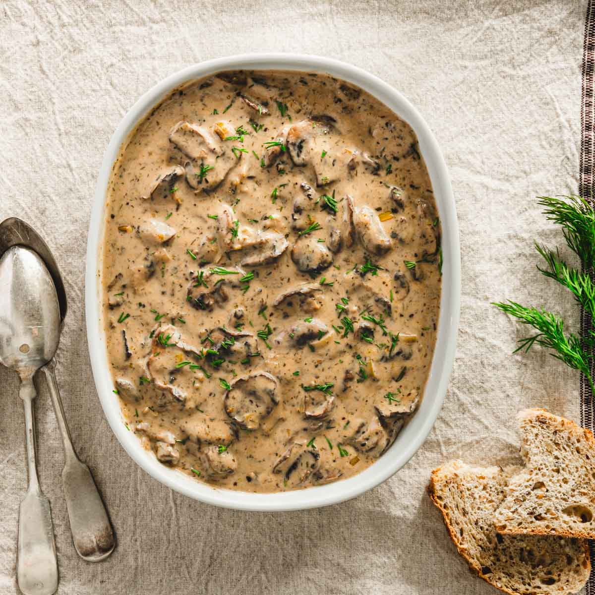 mushroom sauce in a serving dish, on a napkin, pieces of bread, fresh dill