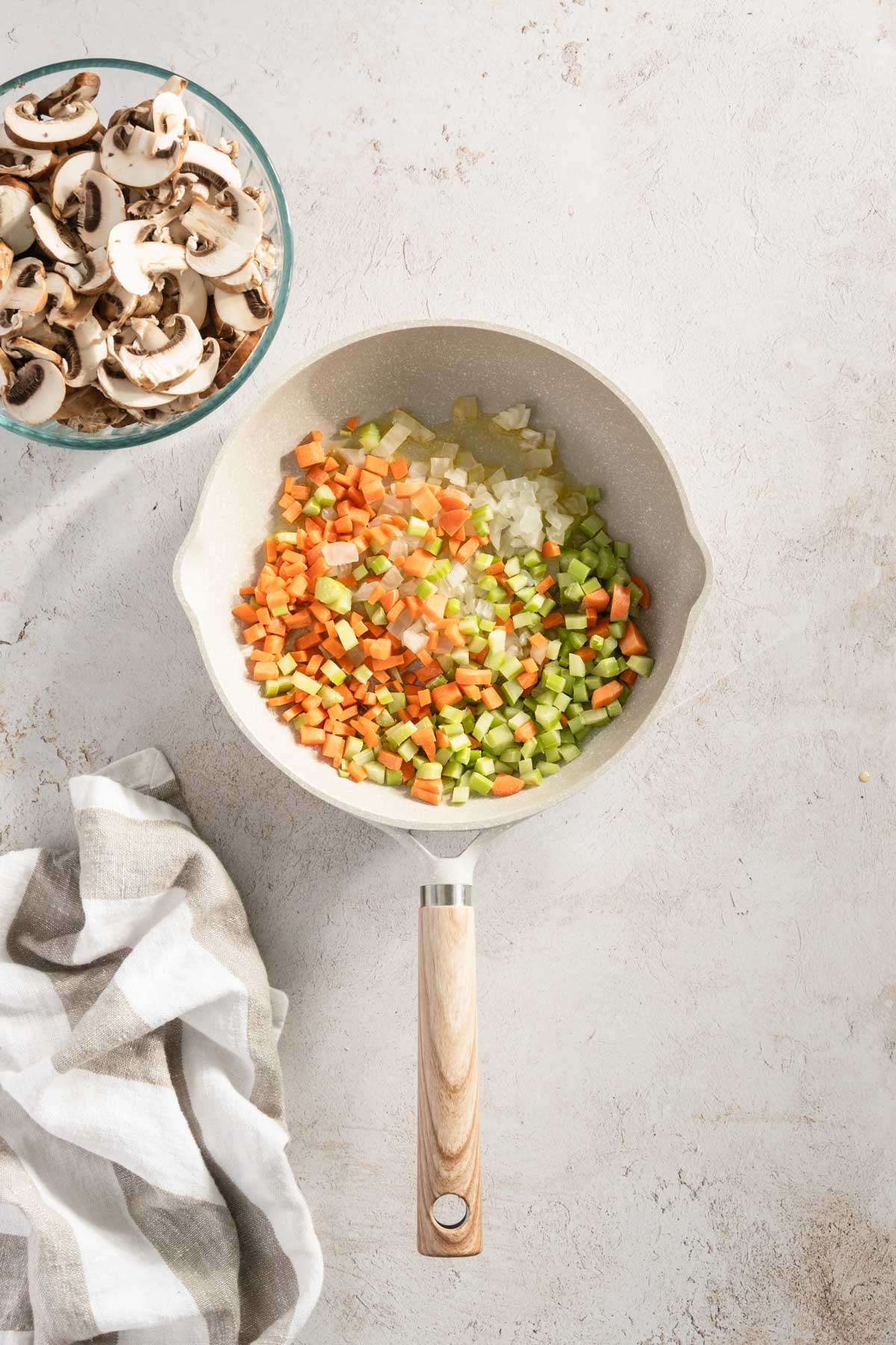 frying pan with chopped carrots, celery and onion; small bowl with sliced mushrooms