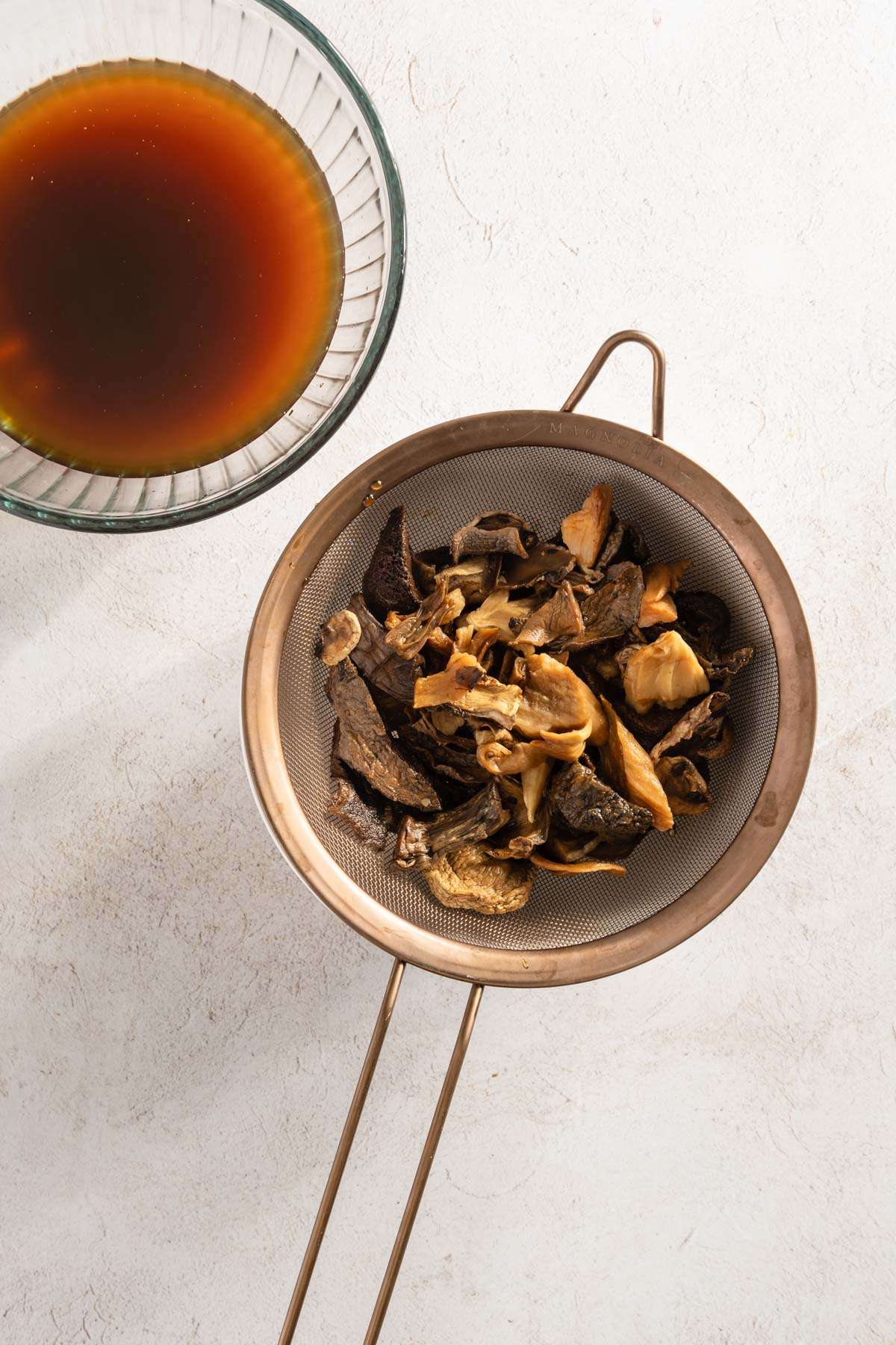 strainer with rehydrated mushrooms, bowl with mushroom water