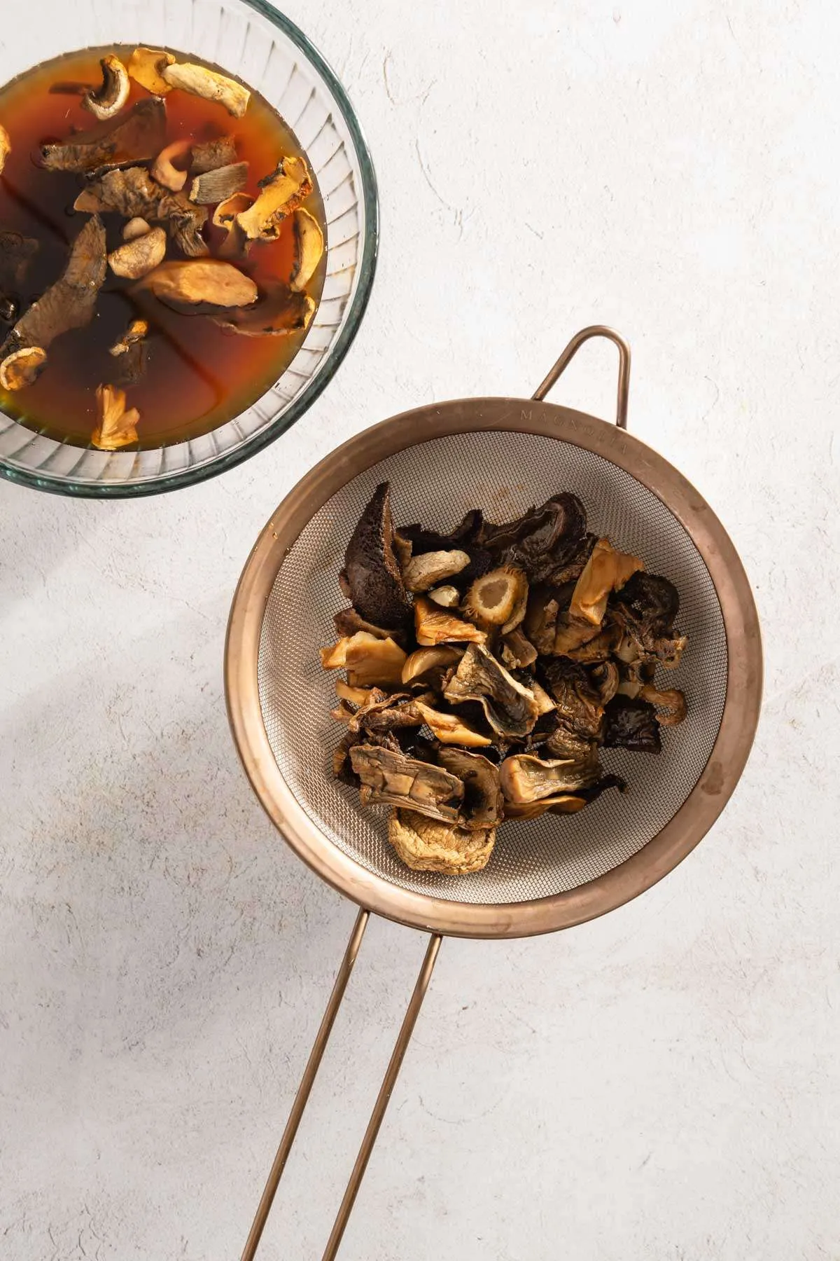 strainer with rehydrated mushrooms, bowl with mushrooms in water