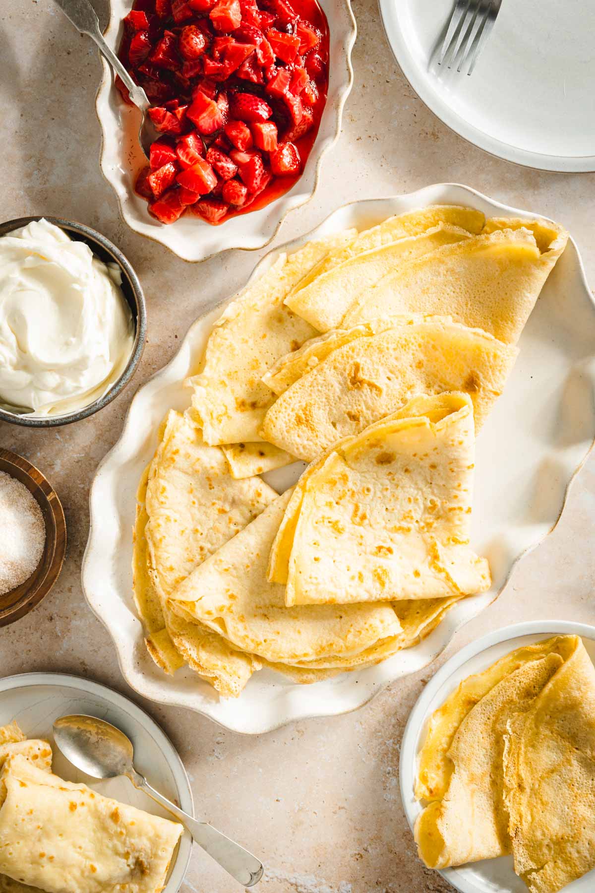 nalesniki on a serving platter, dish with strawberries, sour cream, sugar