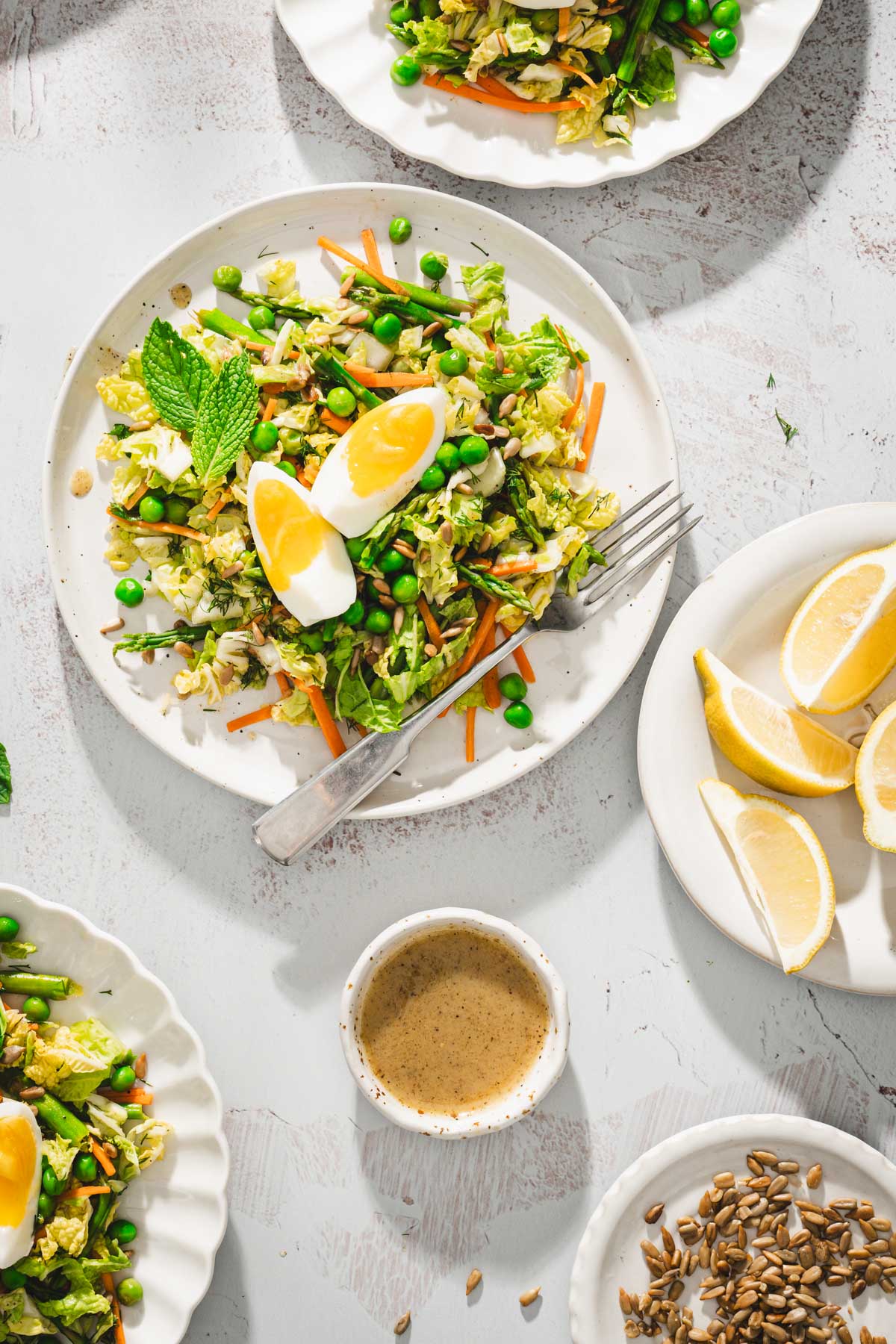 close up of a plate with napa salad, jammy eggs, dish with lemon wedges