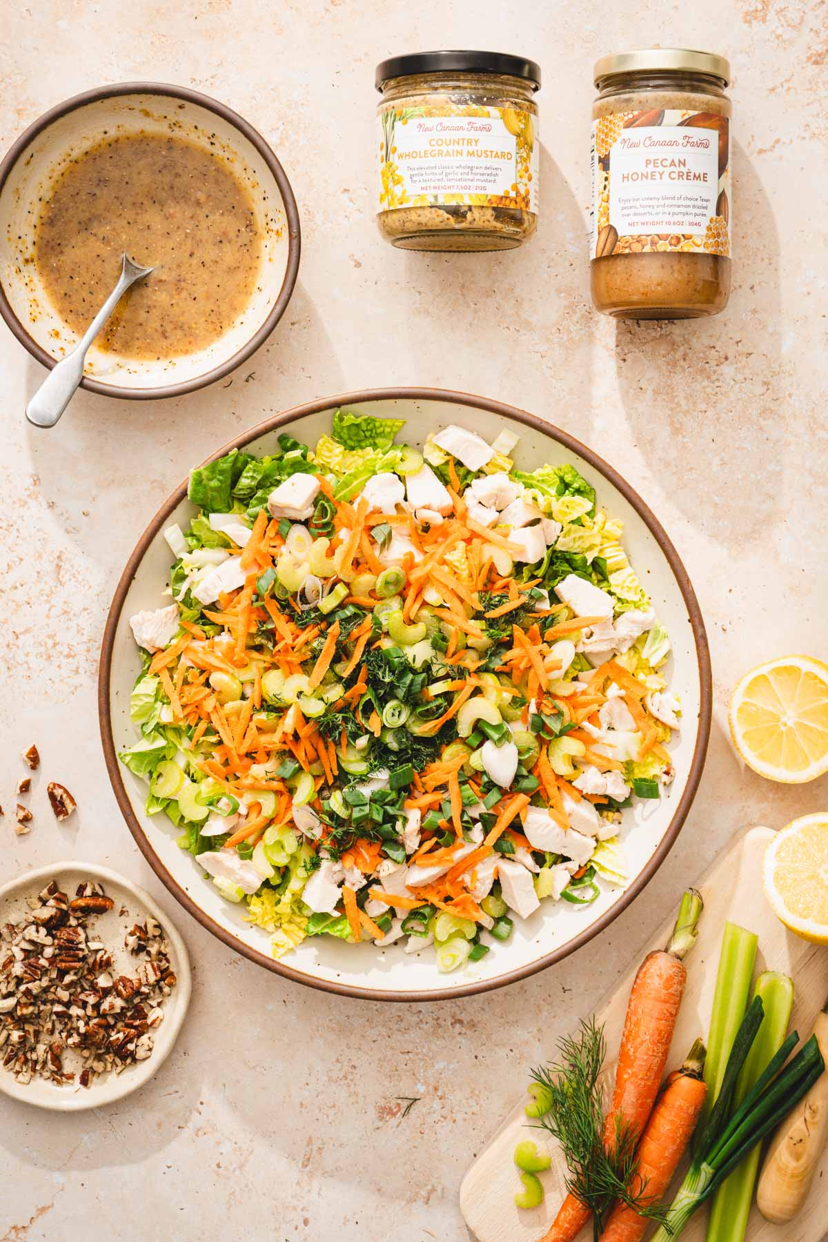 large bowl with prepared salad, bowl with dressing, brand jars