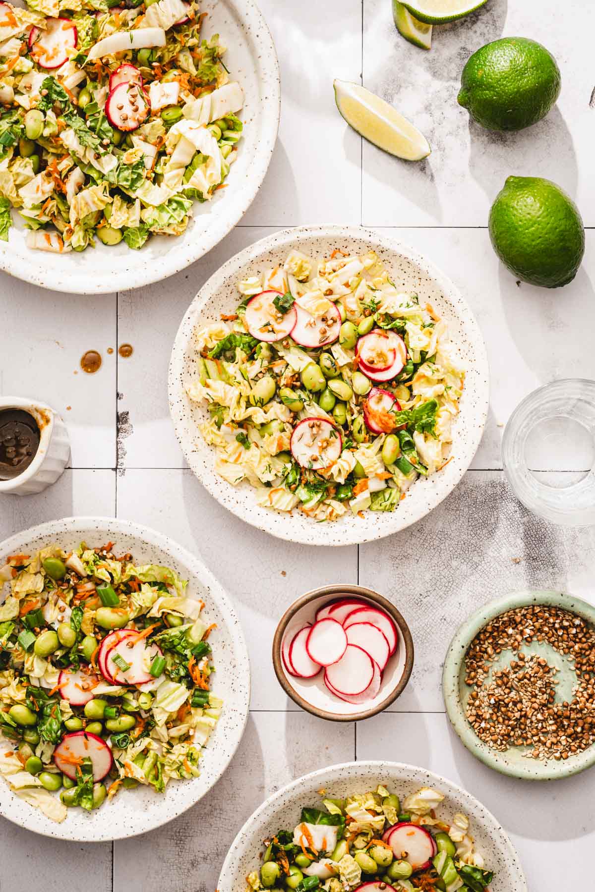 various bowls with the napa cabbage salad, dish with radishes, fresh limes